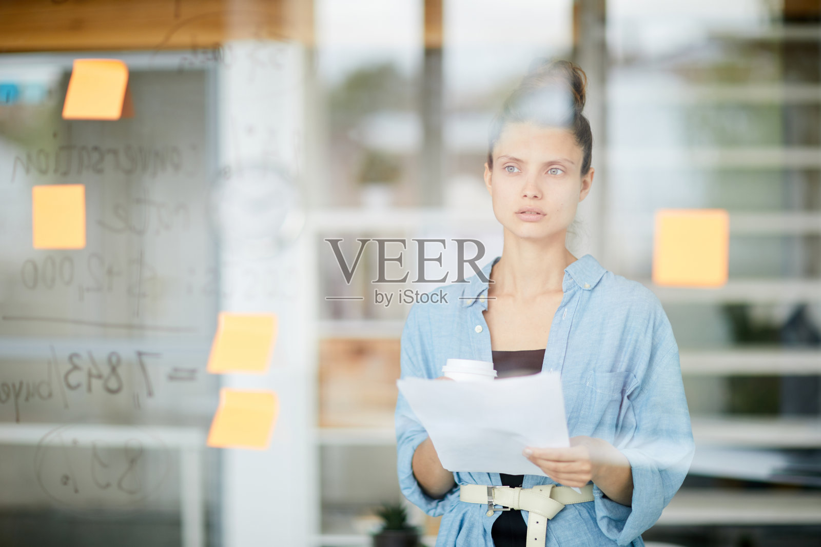 在现代的办公室里,一边喝咖啡,一边分析玻璃板上的笔记和阅读报告照片摄影图片