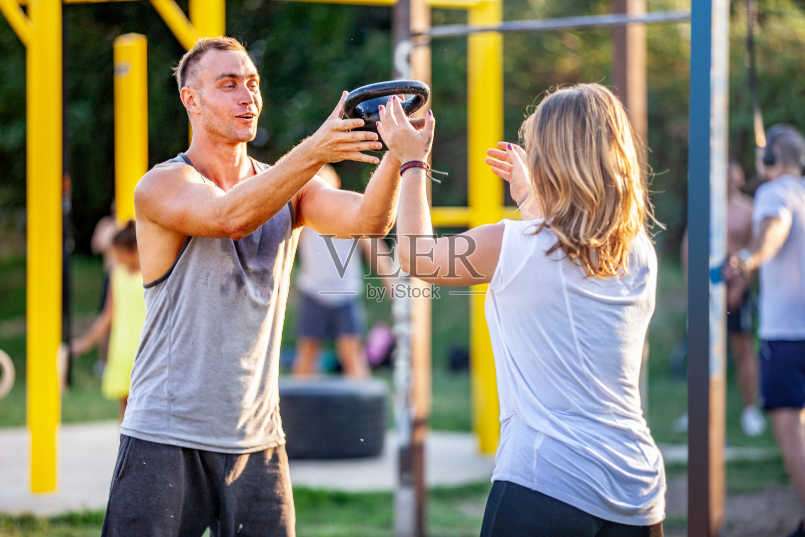 青年男子和女子扔和接壶铃重量户外照片摄影图片