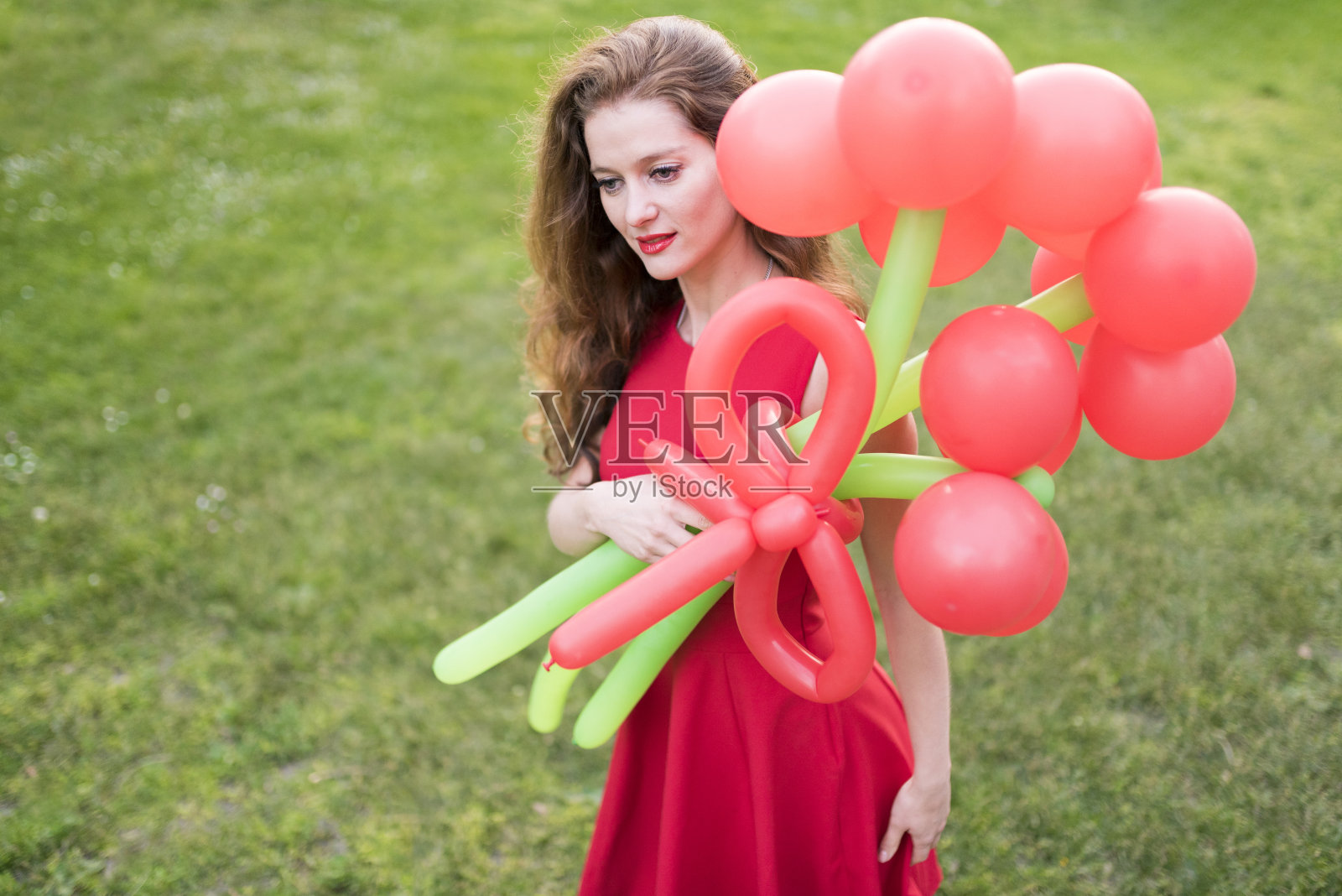 一个孤独的女人穿着红色衣服,在公园里捧着气球照片摄影图片