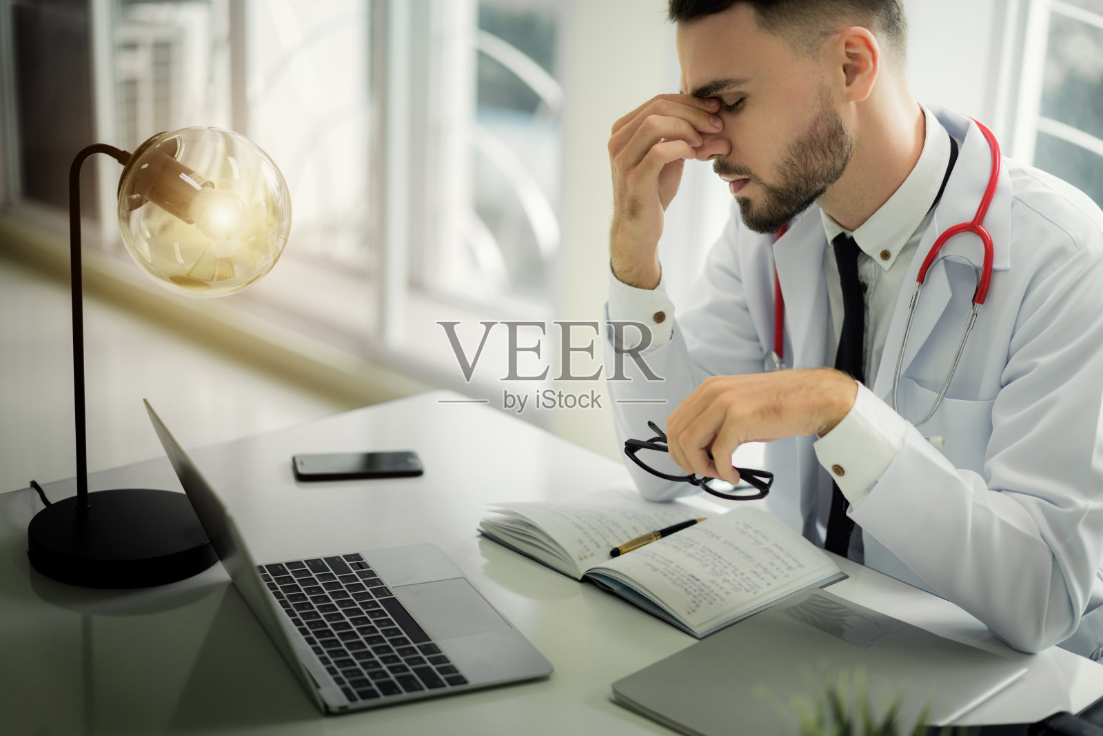 医生们表情严肃,工作压力很大。医生在工作时感到头痛,在治疗病人时感到压力。照片摄影图片