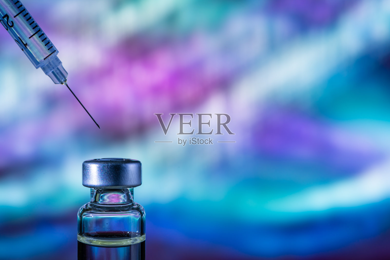 彩色抽象背景上的针管指向疫苗瓶照片摄影图片