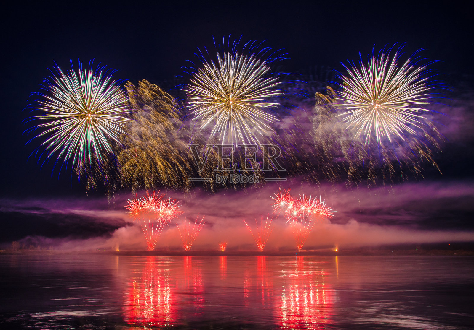美丽多彩的节日烟花映在水中,以黑色的天空为背景,特写,长曝光照片摄影图片