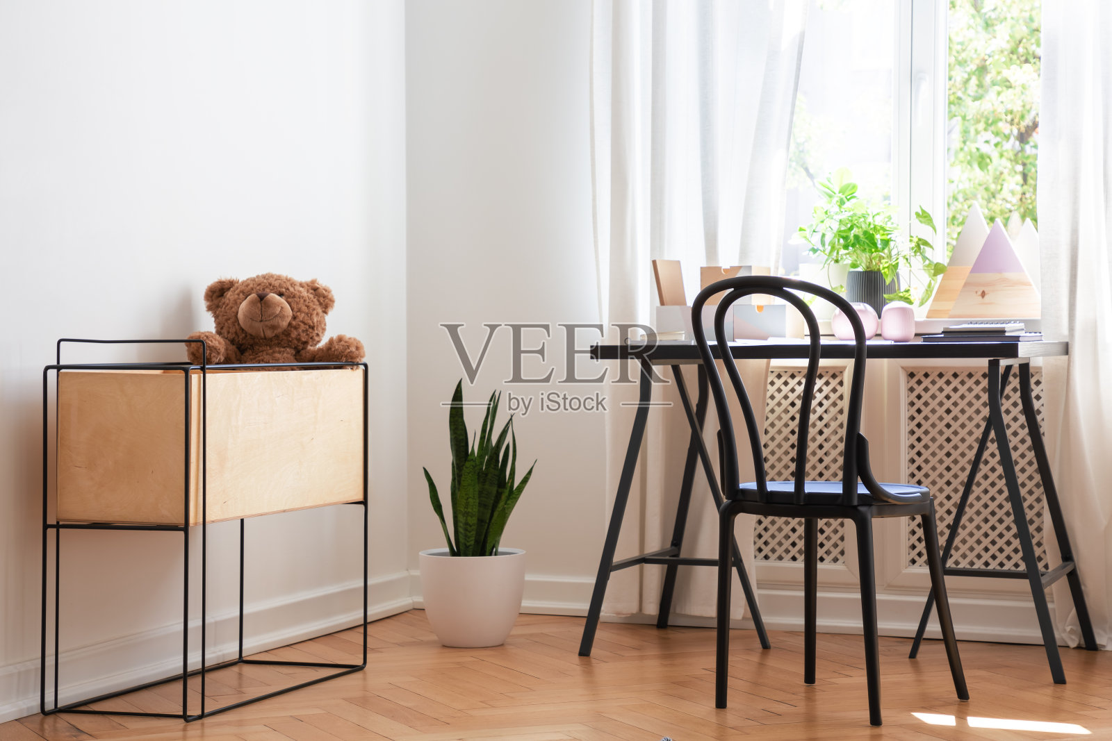 毛绒玩具在盒子旁边的椅子在书桌在青少年的房间内部有窗户和植物。真实的照片照片摄影图片