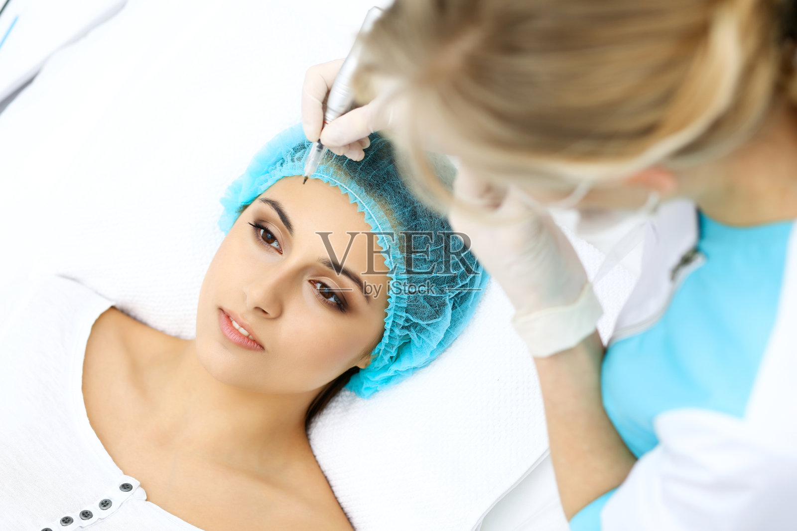 专业美容师在女人脸上纹眉。美容院永久眉妆,特写。美容治疗照片摄影图片