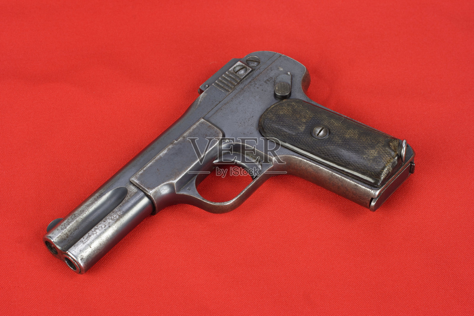 红色背景上的旧生锈手枪照片摄影图片