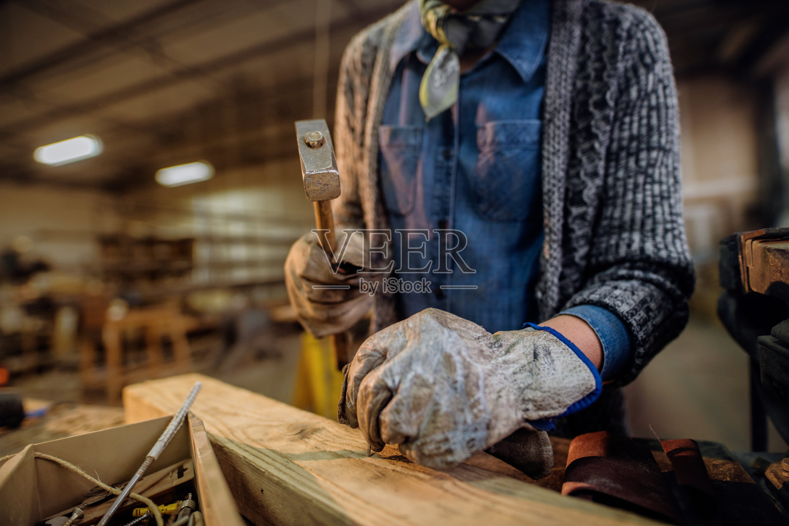 在木工车间钉钉子的妇女。手的闭合。照片摄影图片