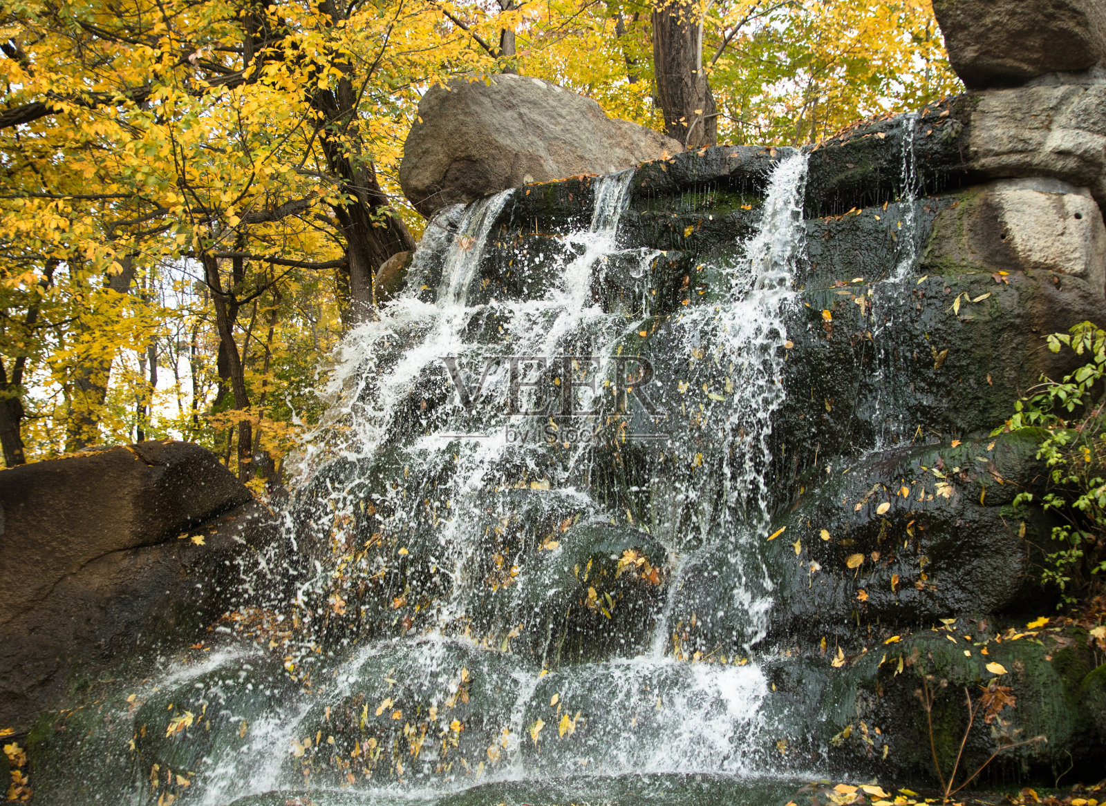 瀑布从秋季公园的岩石上倾泻而下照片摄影图片