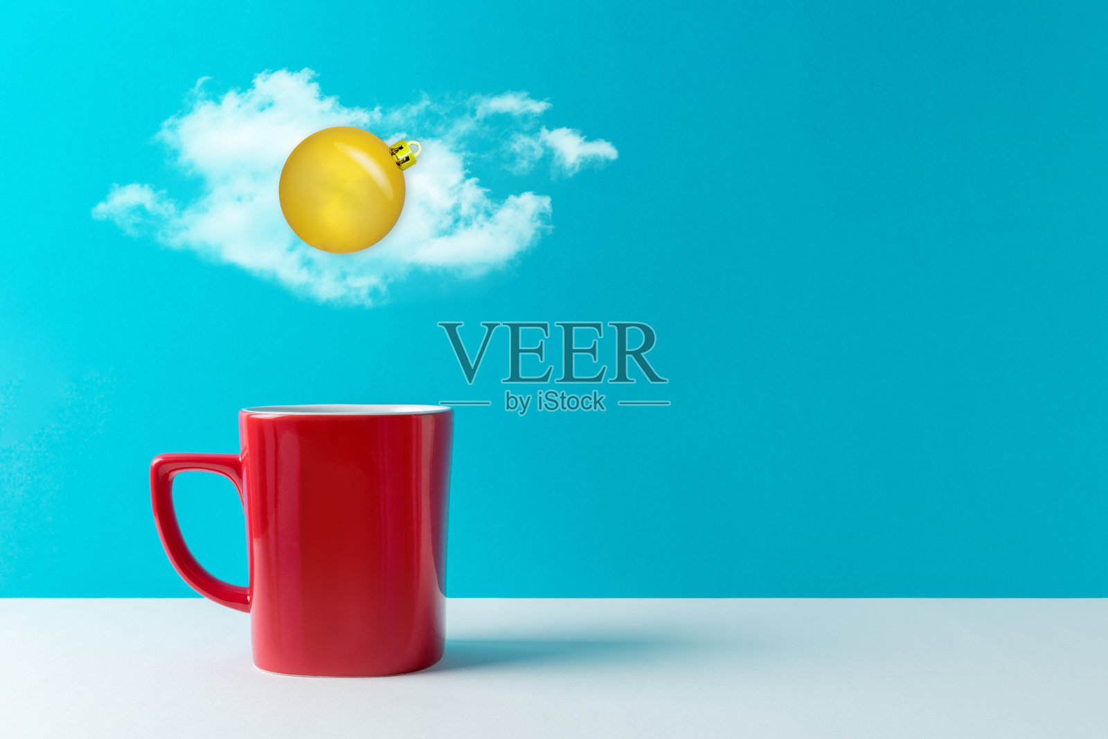 由金色圣诞装饰物制成的鸡蛋和蓝色背景的咖啡杯上方的云朵。圣诞节的概念。照片摄影图片