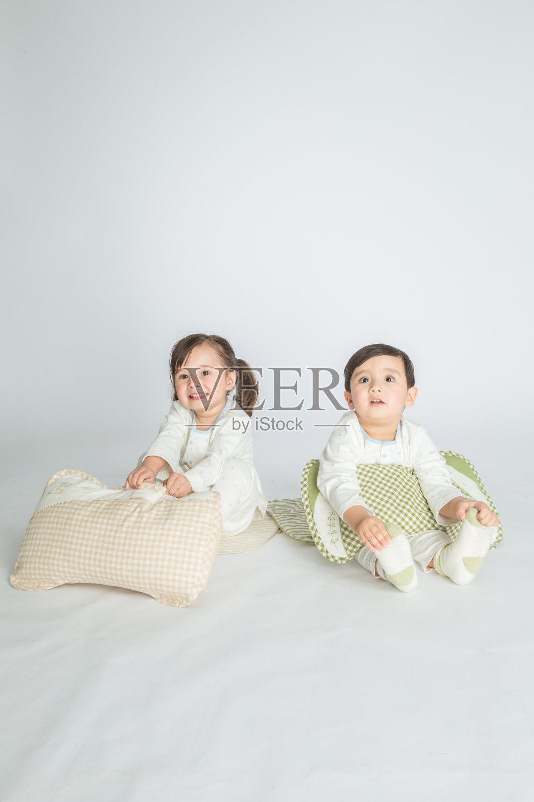 快乐的小女孩和小男孩在卧室的地板上抱着一个枕头。照片摄影图片