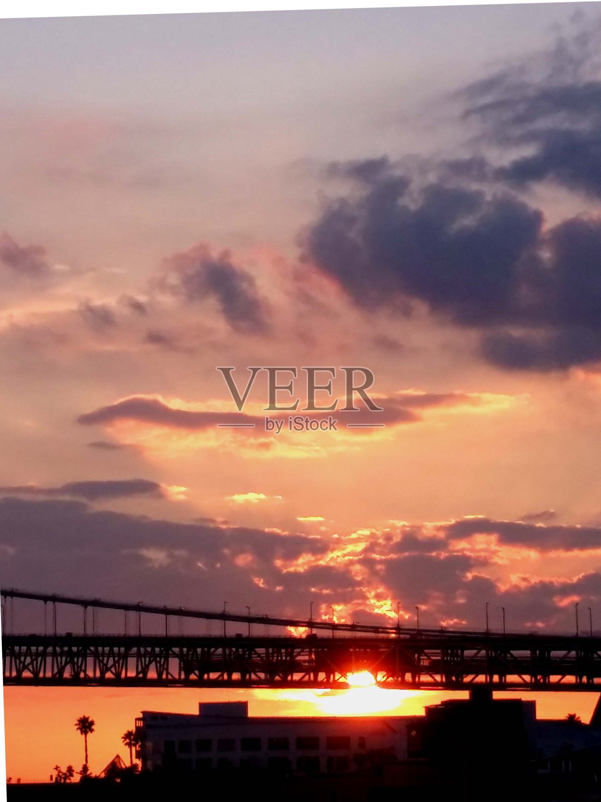 太阳落在明石海峡大桥上。照片摄影图片