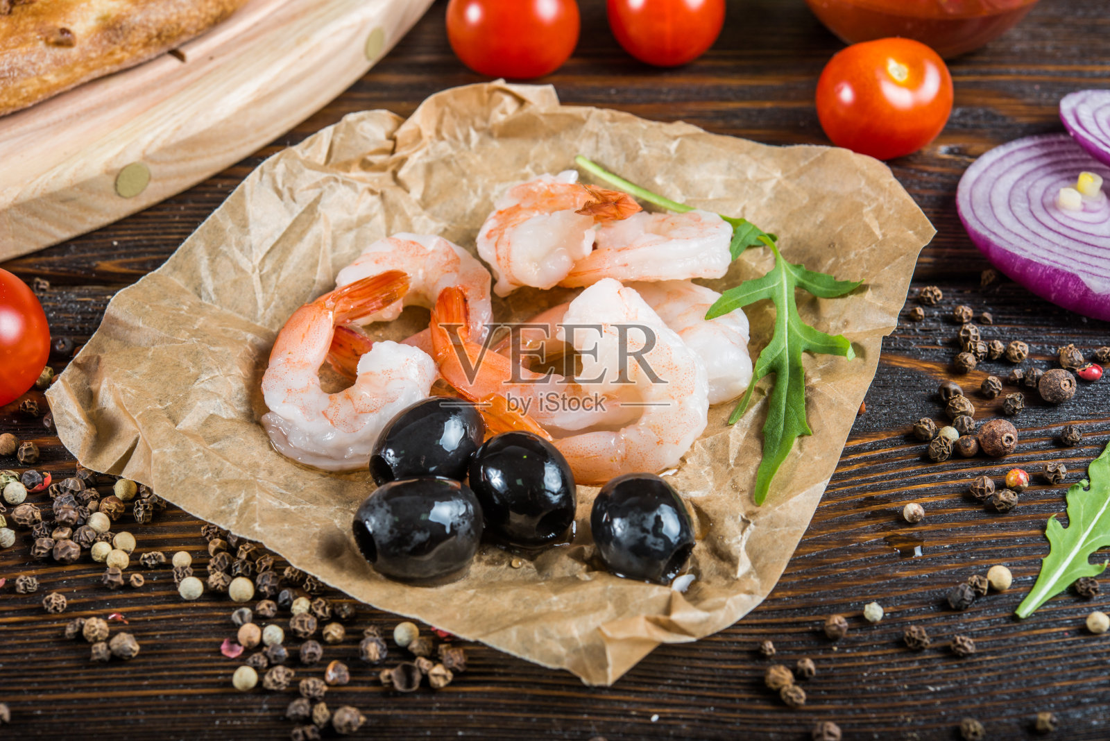 宏。食品背景设计。海鲜,虾和橄榄,在深色的树林里。比萨配料。照片摄影图片