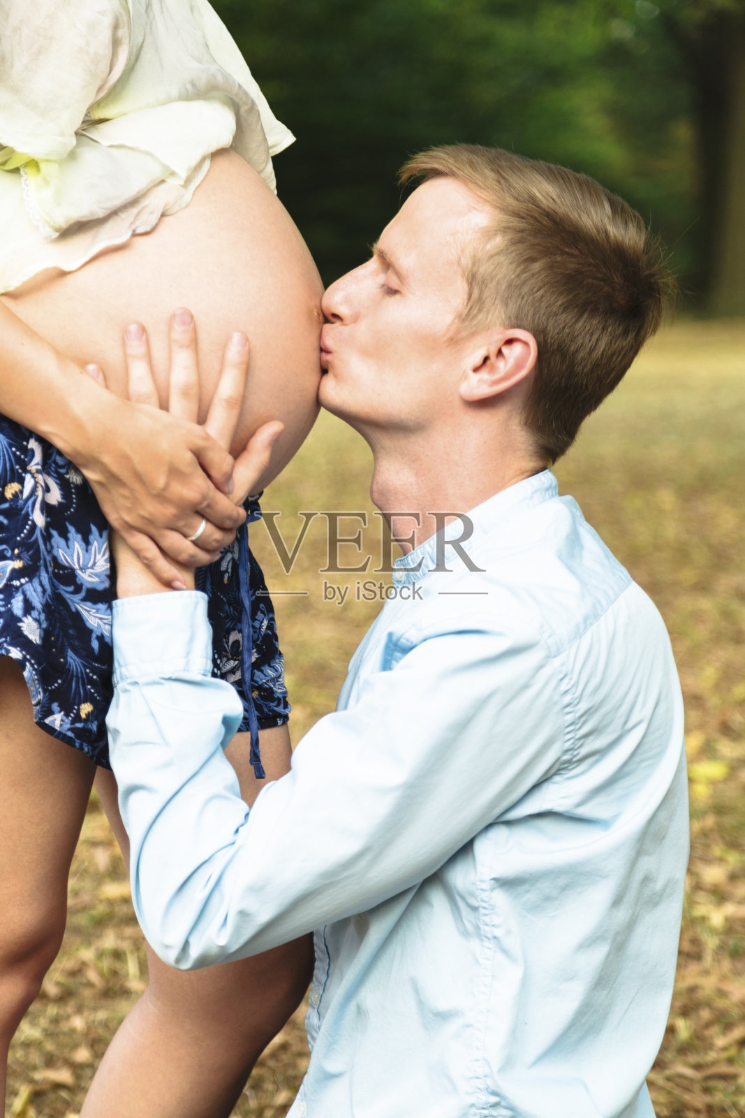 青年男子在户外亲吻孕妇的肚子照片摄影图片