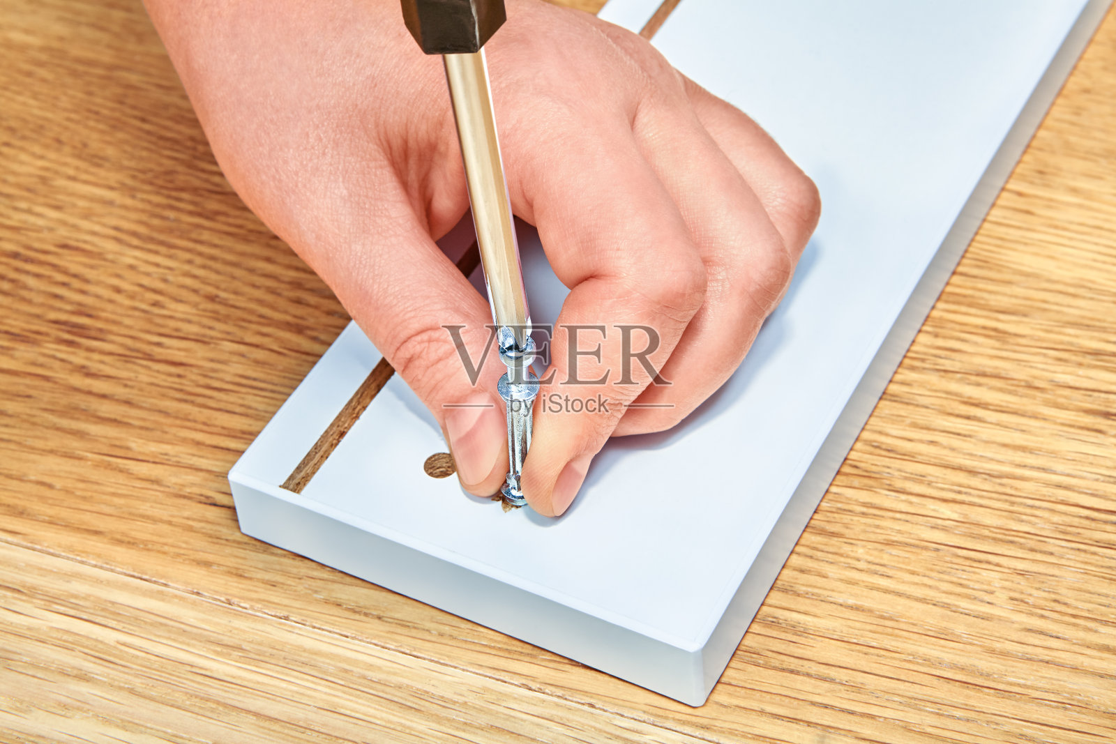 杂工用螺丝刀拧紧钢制凸轮销和家具。照片摄影图片