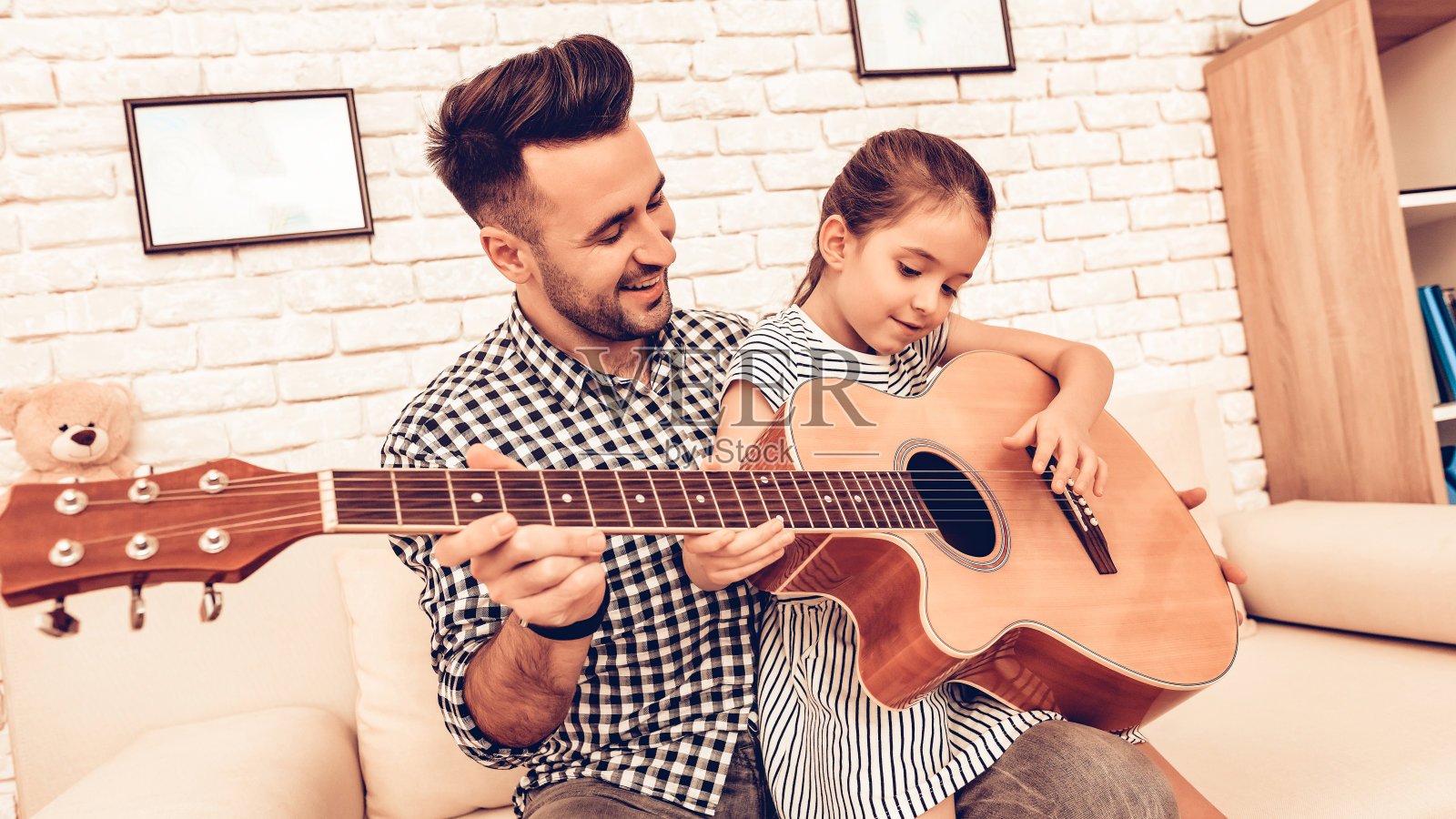 男人和女孩一起在公寓里弹吉他。照片摄影图片