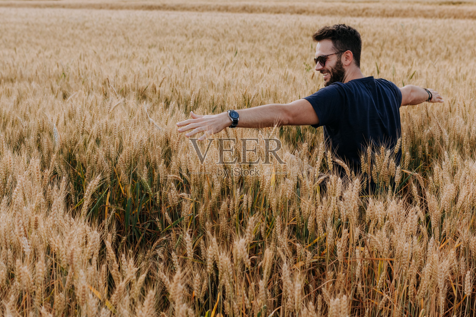 年轻人张开双臂站在麦田里照片摄影图片