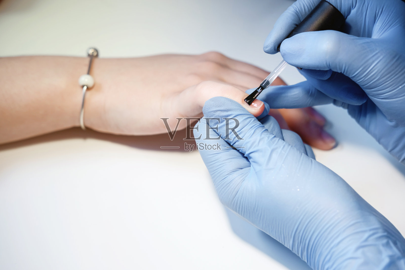 女孩做美甲,漂亮的女性手部美甲,涂指甲油,乳胶手套照片摄影图片