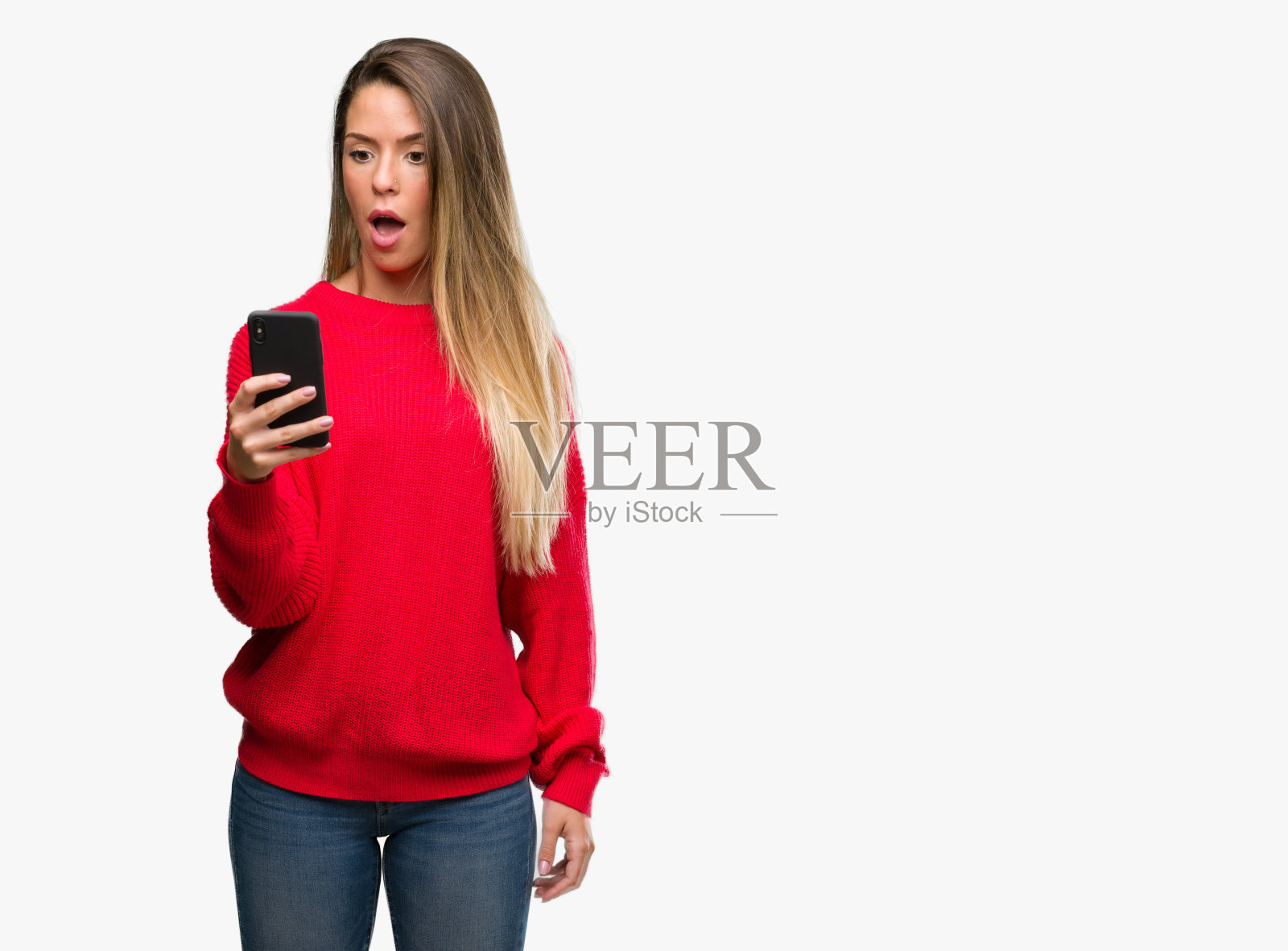 美丽的年轻女子使用智能手机吓了一跳,脸上带着惊讶、害怕和兴奋的恐惧表情照片摄影图片