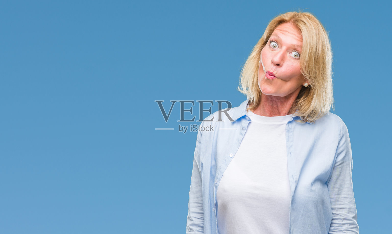 中年金发女人在孤立的背景,使鱼脸与嘴唇,疯狂和滑稽的手势。有趣的表情。照片摄影图片