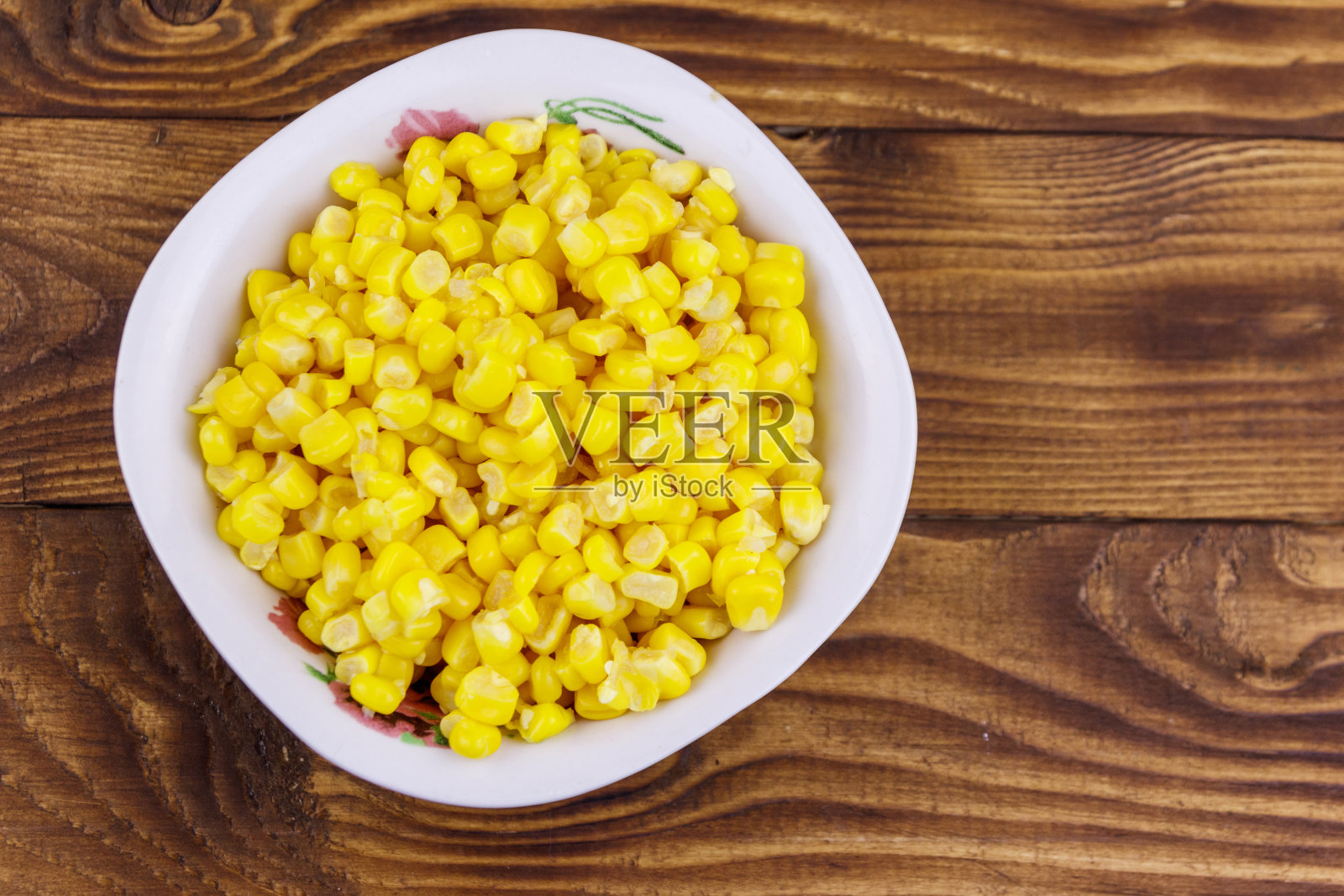在木桌上的碗里装着甜玉米罐头照片摄影图片