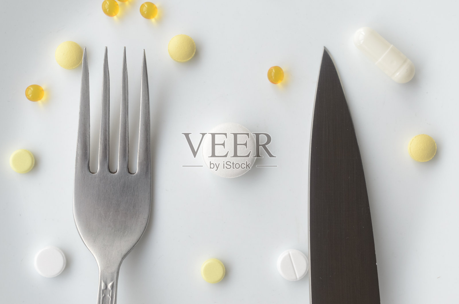 药丸放在白色盘子里,用刀叉。强加毒品的概念。照片摄影图片