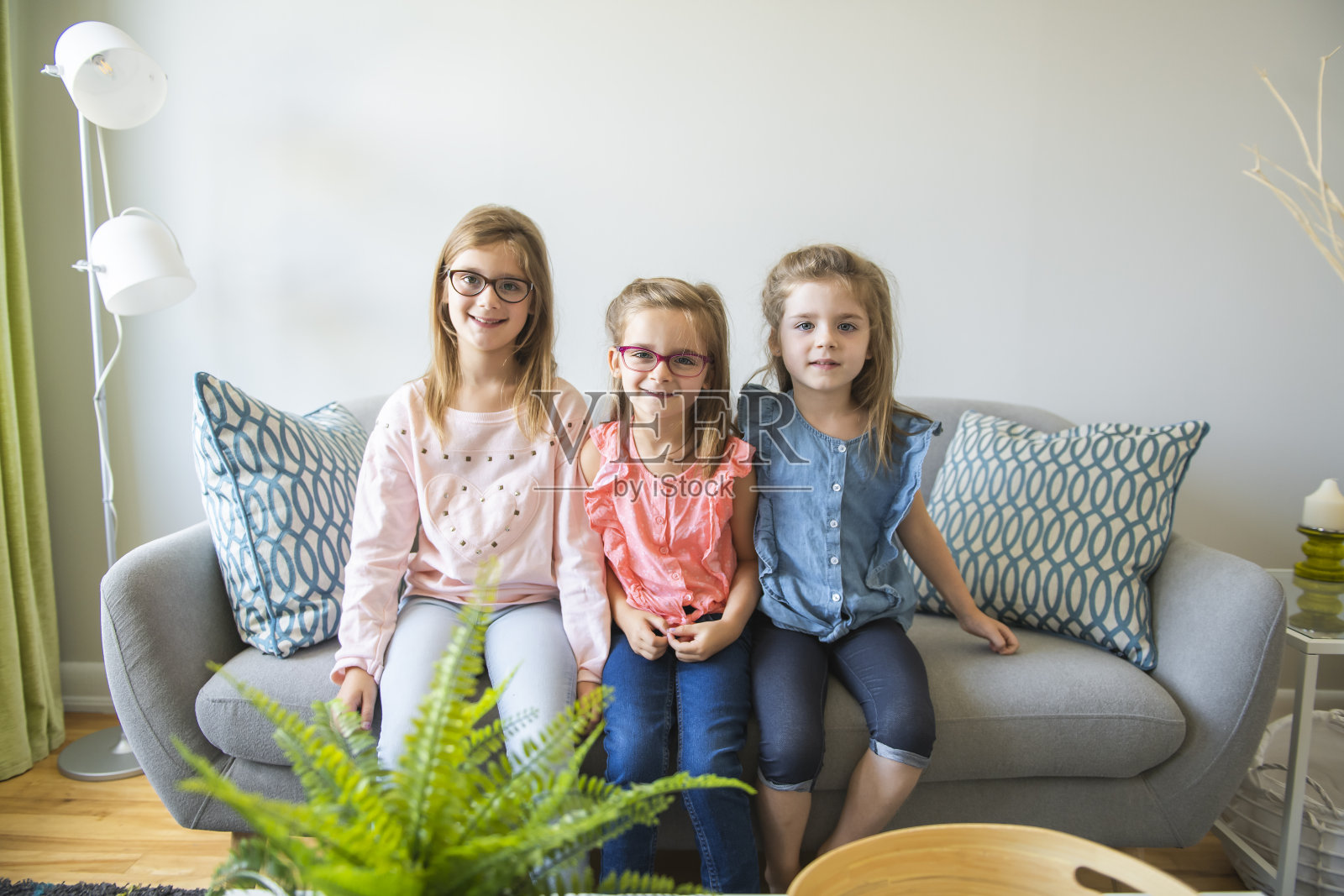 三个姐妹的女孩坐在家里的沙发上照片摄影图片