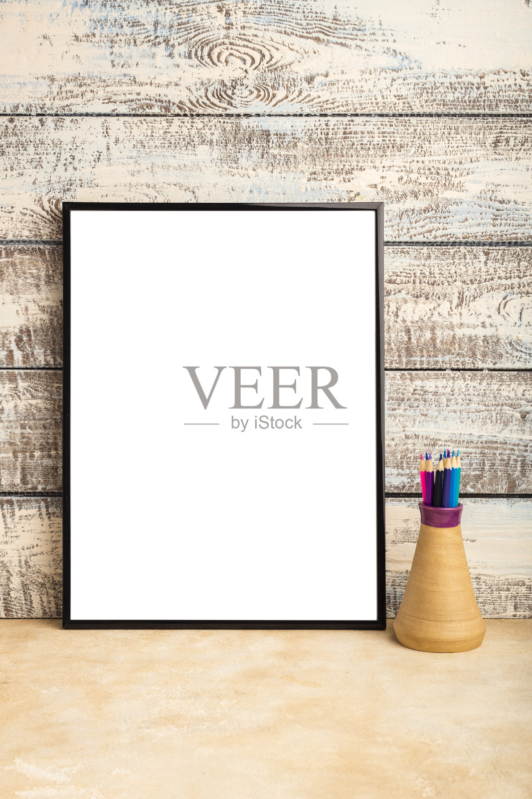 一个空框海报的模拟在木板墙上。花瓶里的彩色铅笔照片摄影图片