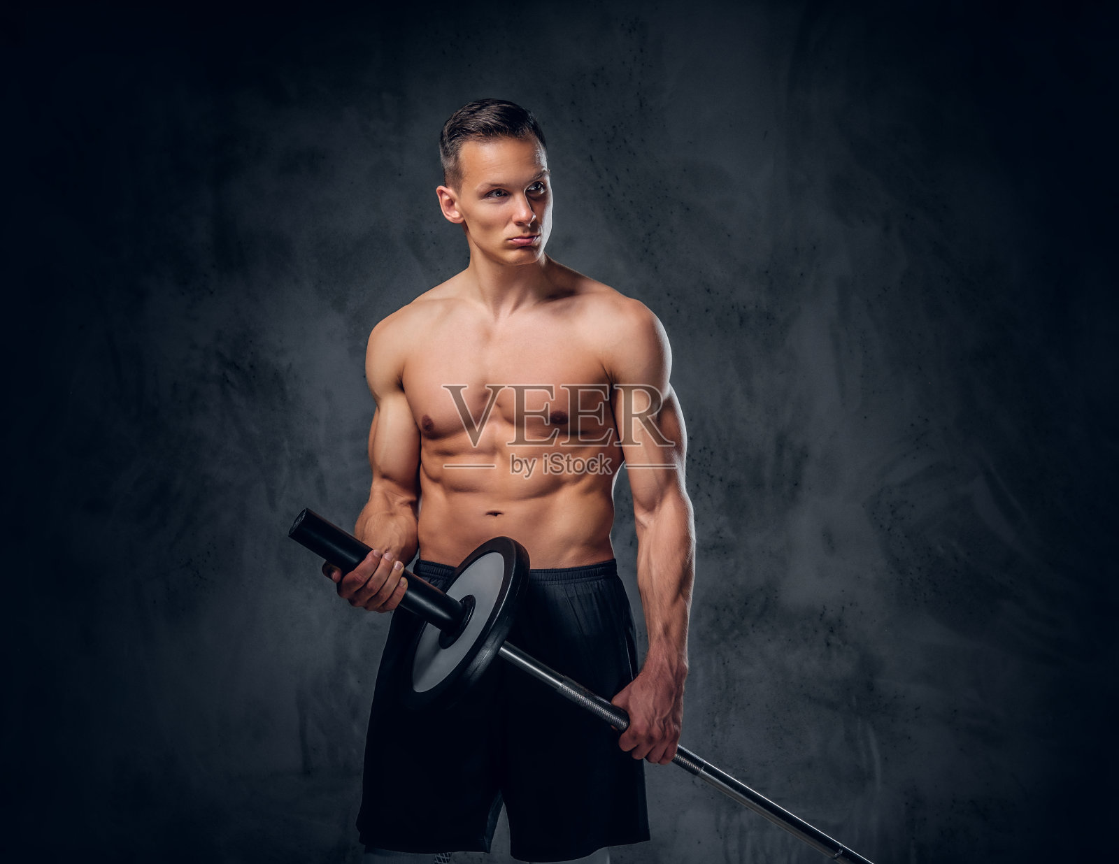 赤裸上身的男性手持杠铃。照片摄影图片