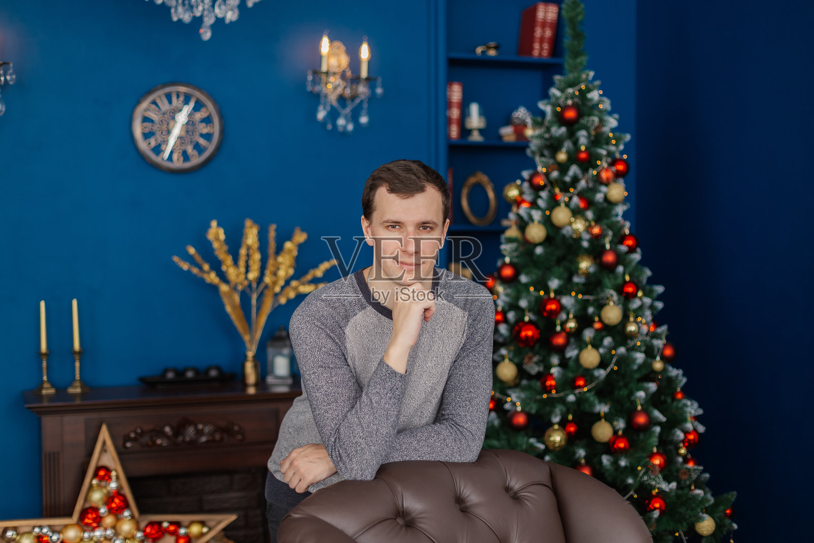 一个很帅的男人正站在新年房间的椅子旁边照片摄影图片