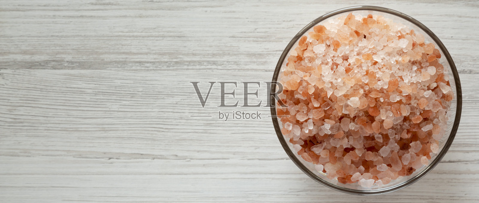 喜马拉雅海盐在一个玻璃碗上白色木制表面,俯视图。平躺着,从上面看。副本的空间。照片摄影图片