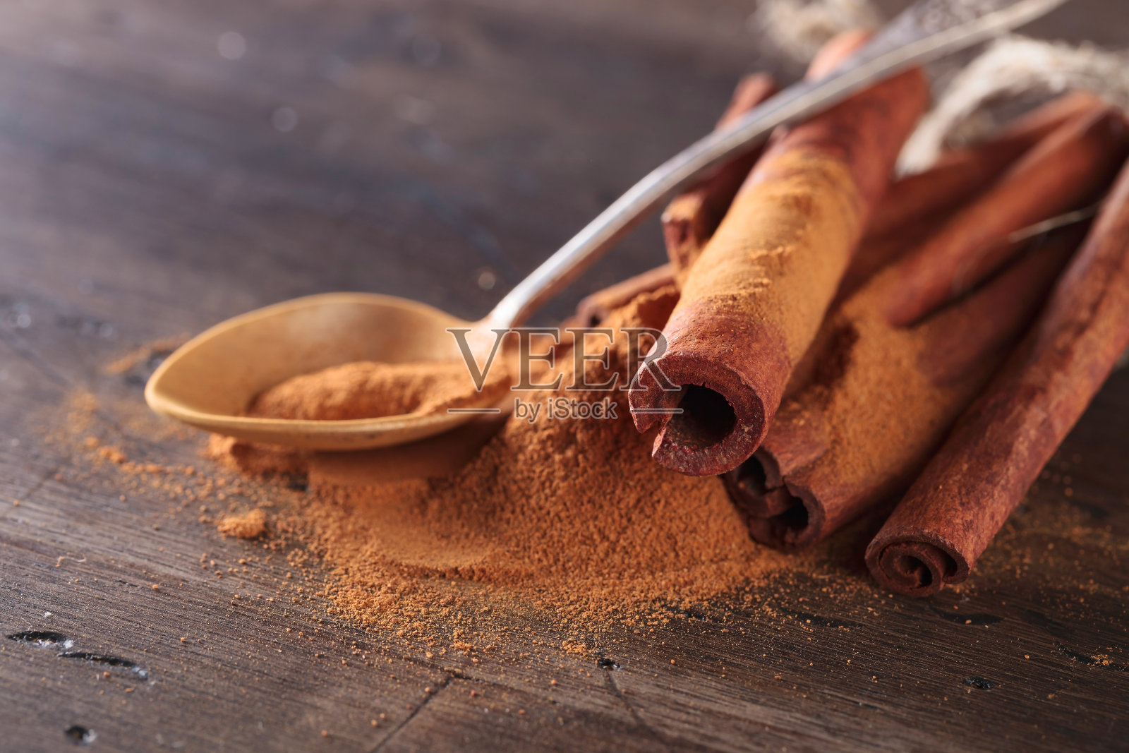 木桌上放着肉桂棒和粉末。照片摄影图片