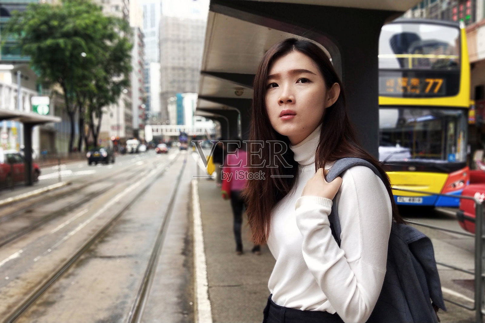 在香港北角的一个巴士站,年轻的亚洲女乘客在等待上电车。一个香港大学生的生活方式,每天坐公车去大学照片摄影图片