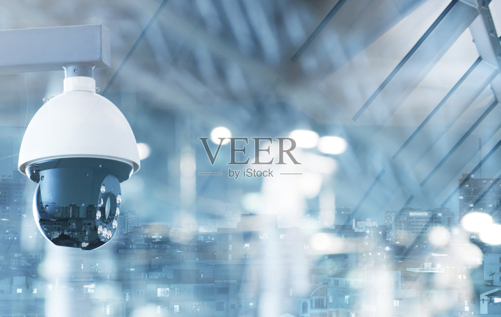 墙上的现代闭路电视摄像头以一个有雾的城市为背景,双曝光模拟照片摄影图片