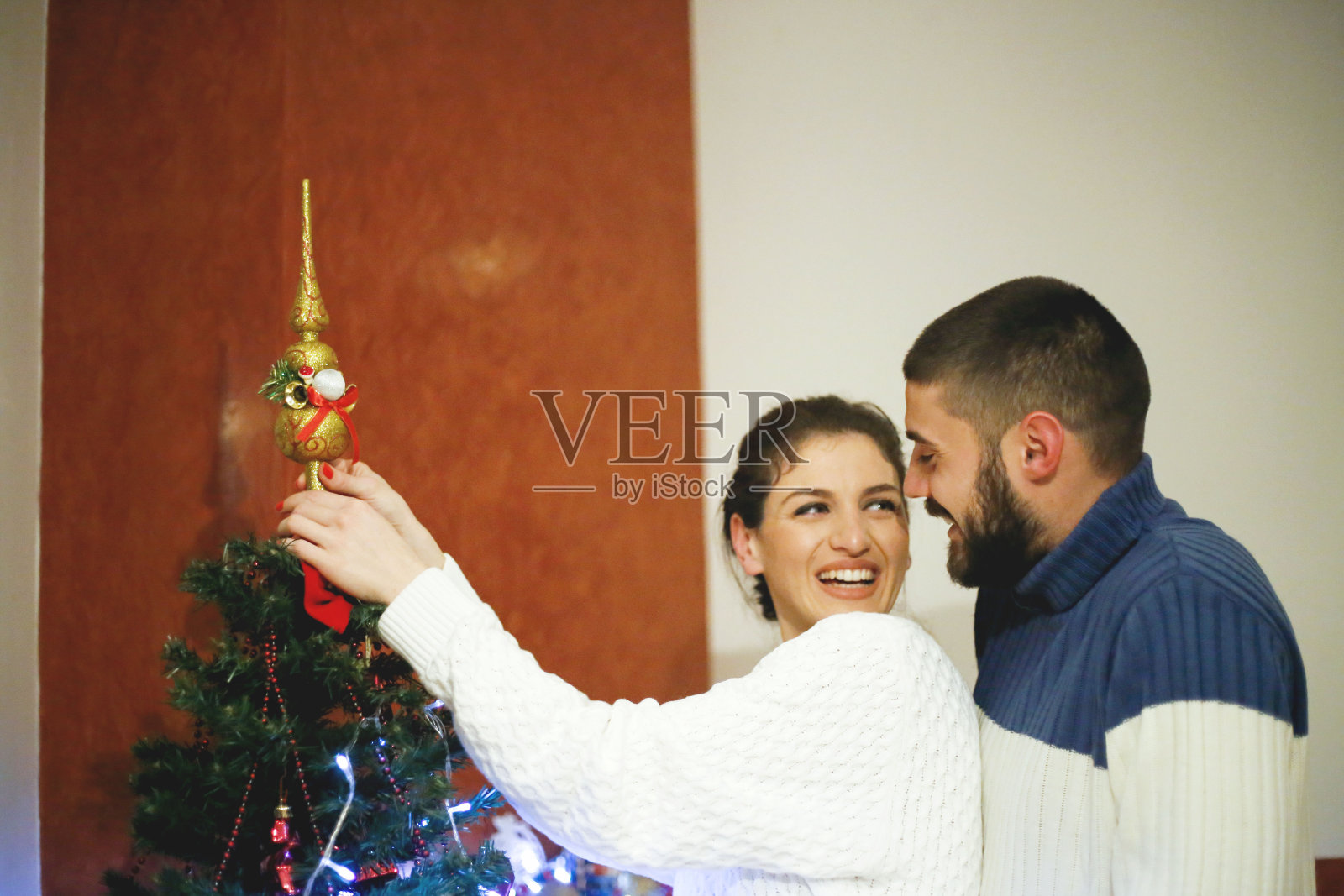 可爱的年轻夫妇装饰圣诞树照片摄影图片