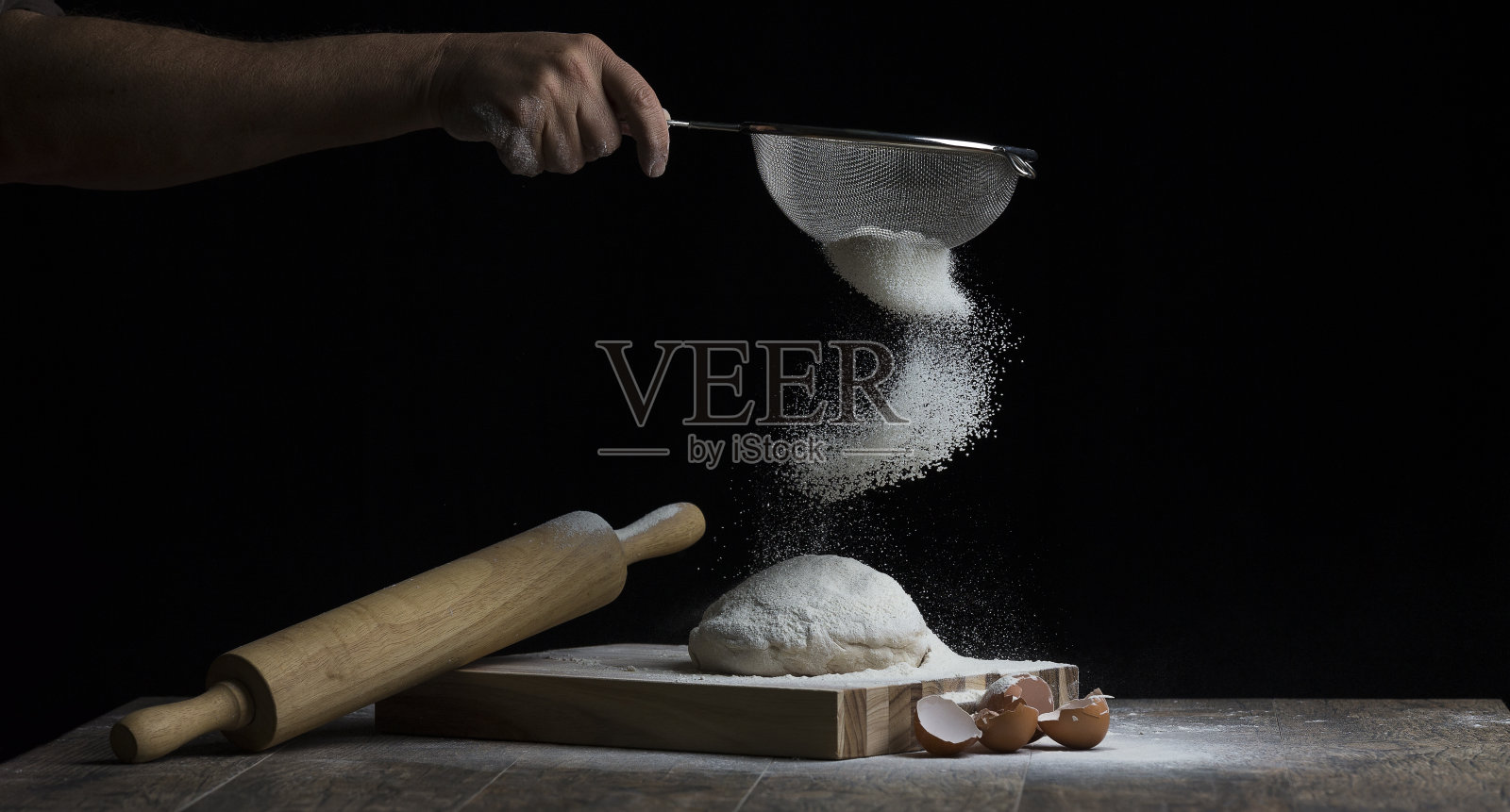 面粉撒在一块有滚轴和鸡蛋的木板上的生面团球上照片摄影图片