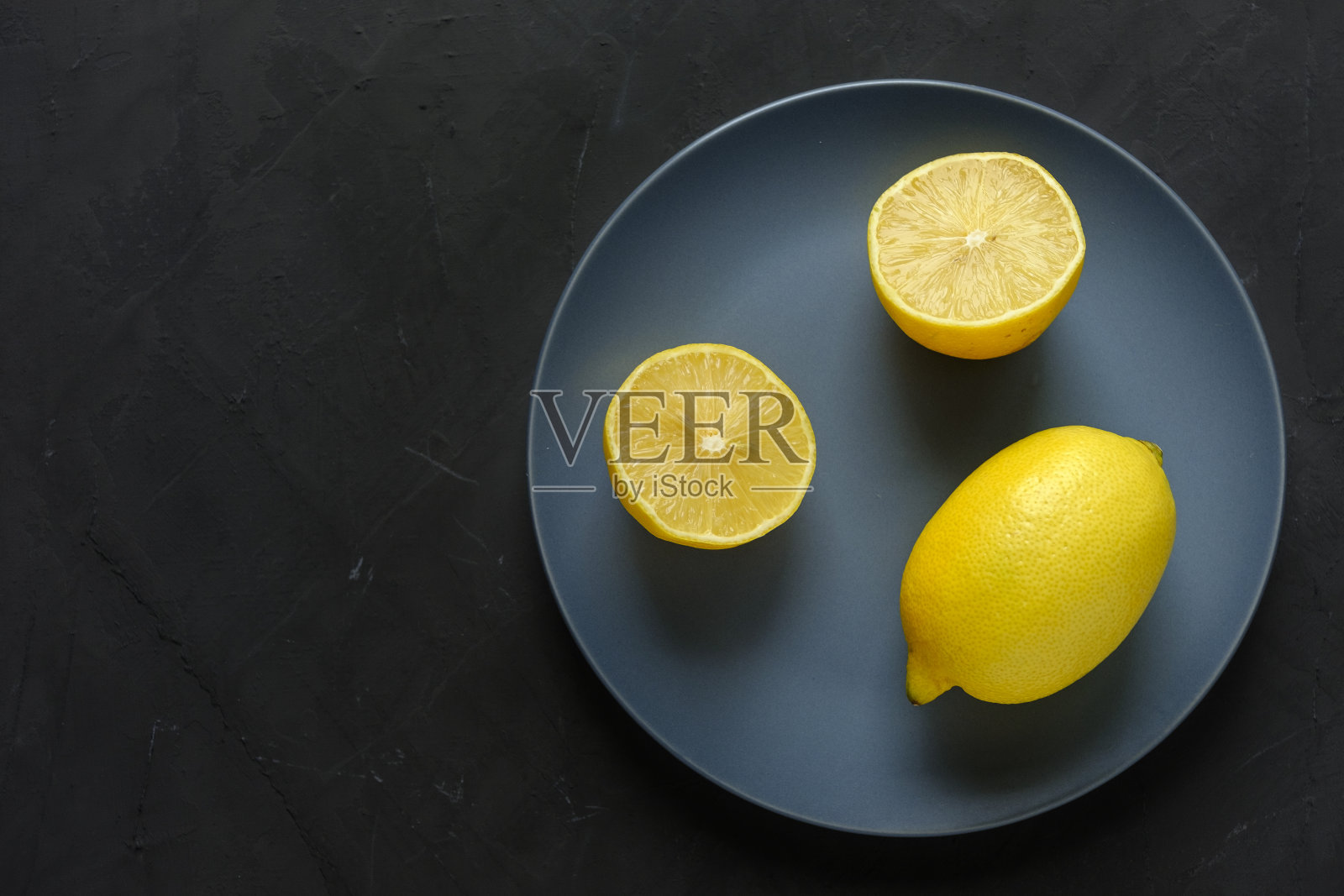 把柠檬切成两半放在盘子里,留出黑色的拷贝空间照片摄影图片