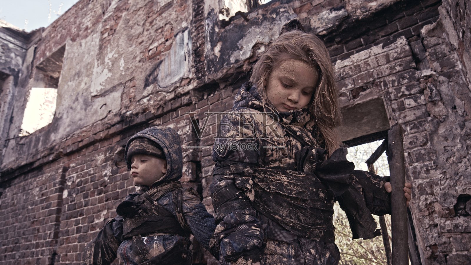 废墟附近饥饿的无家可归的孩子。难民照片摄影图片