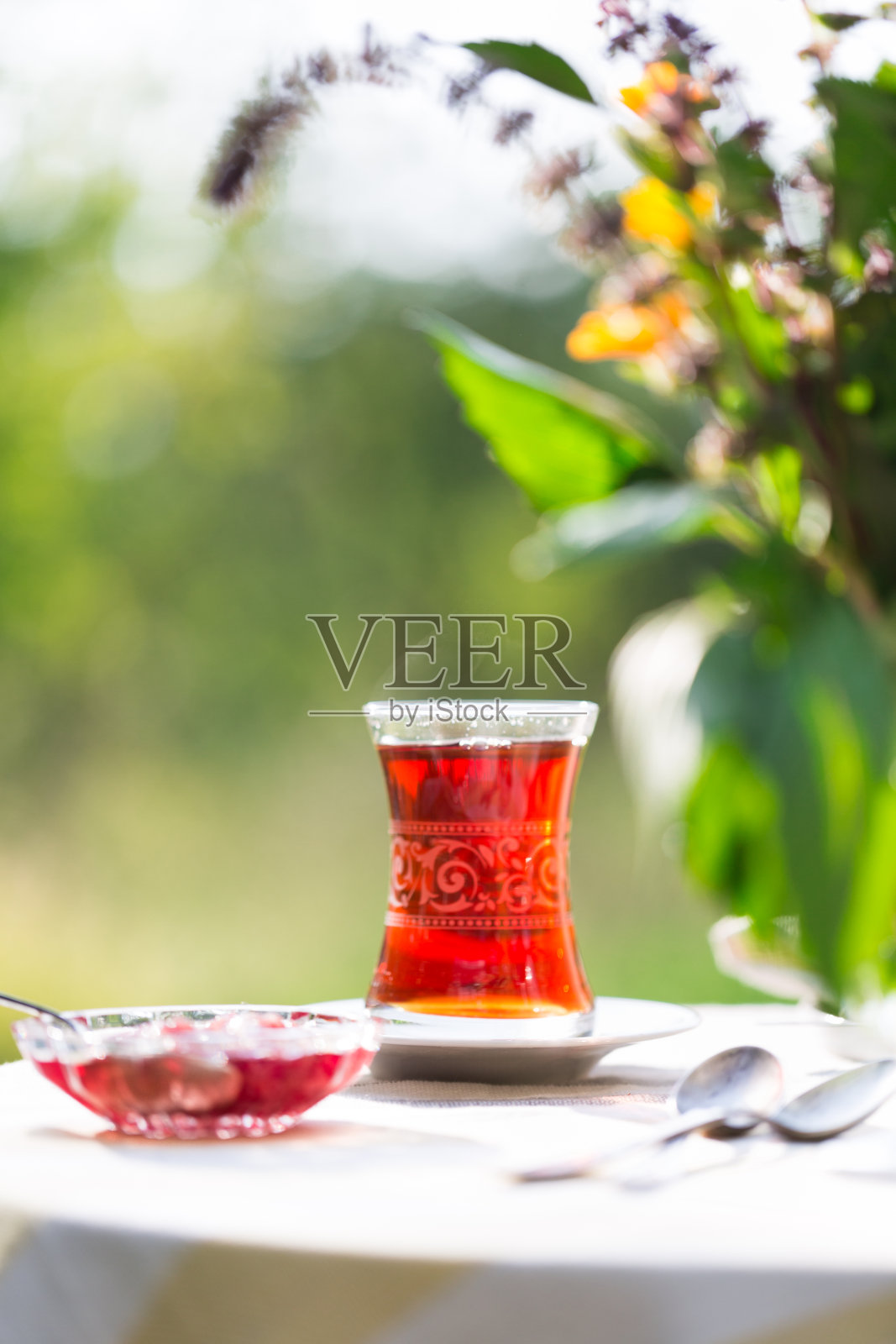 在阳光下的花园,夏日户外,复印空间里,用梨形玻璃杯盛着红茶照片摄影图片
