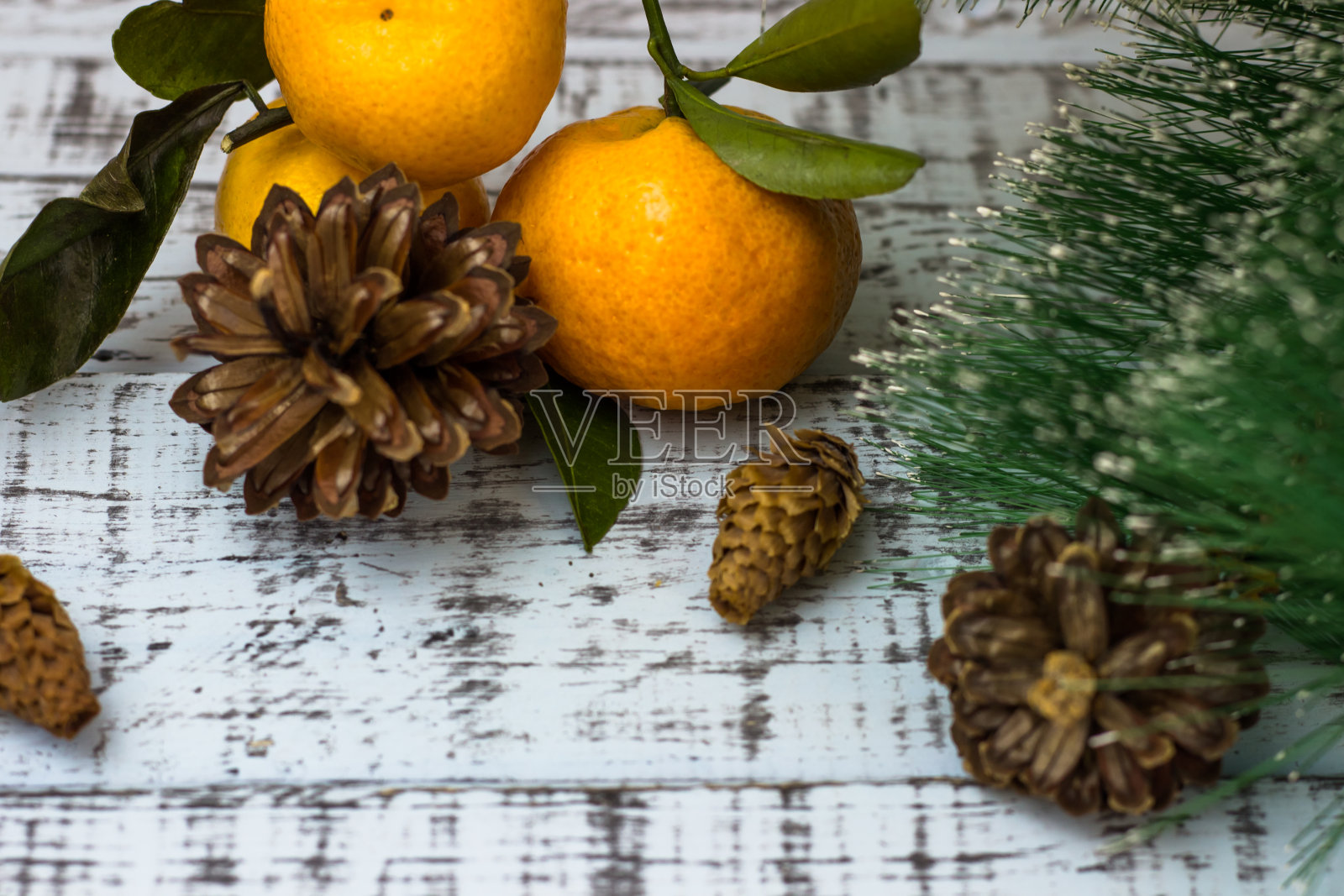 在乡村的背景上放着橘子、圣诞树的树枝和球果。圣诞假期照片摄影图片