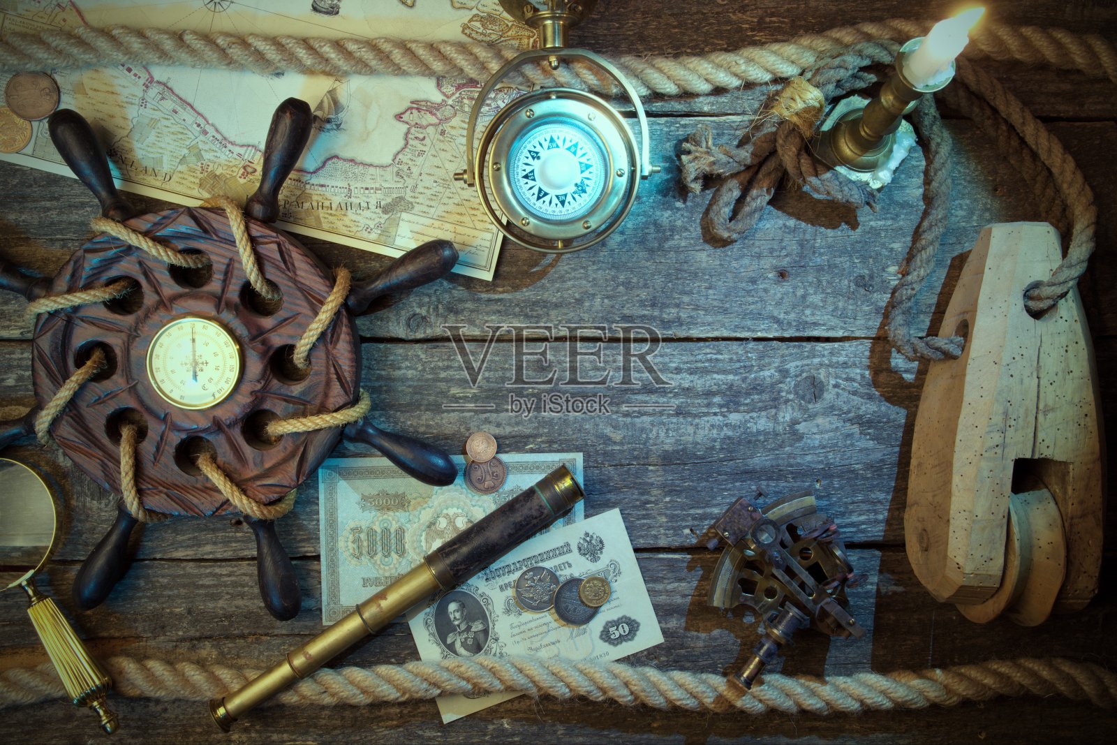旧船的方向盘,指南针,硬币,单片眼镜,放大镜,六分仪,绳子,蜡烛和海盗地图。旅行和海洋雕刻背景。宝罩的概念。复古风格。照片摄影图片