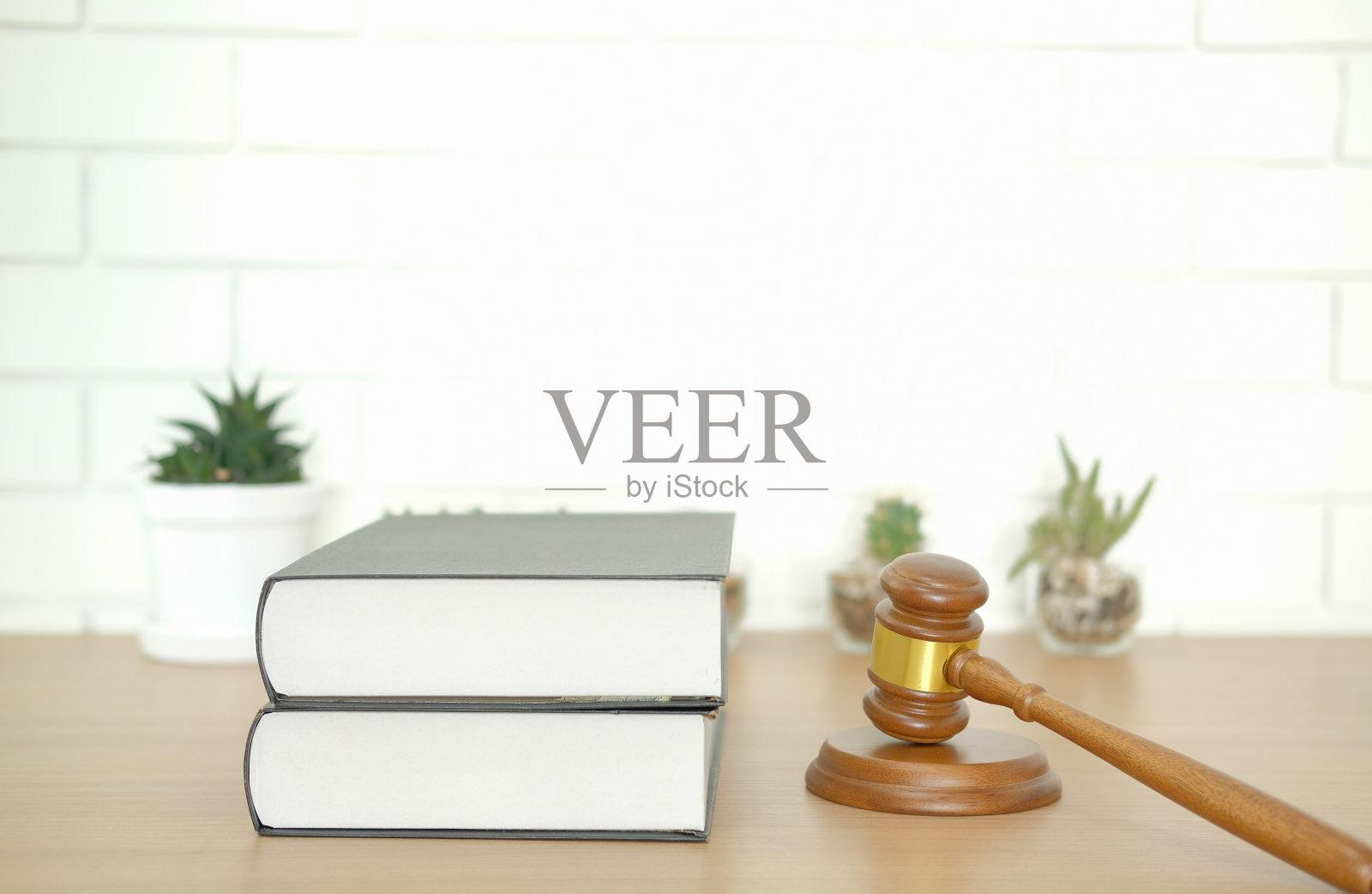 白色砖墙前的法律书籍和法官 gavel照片摄影图片