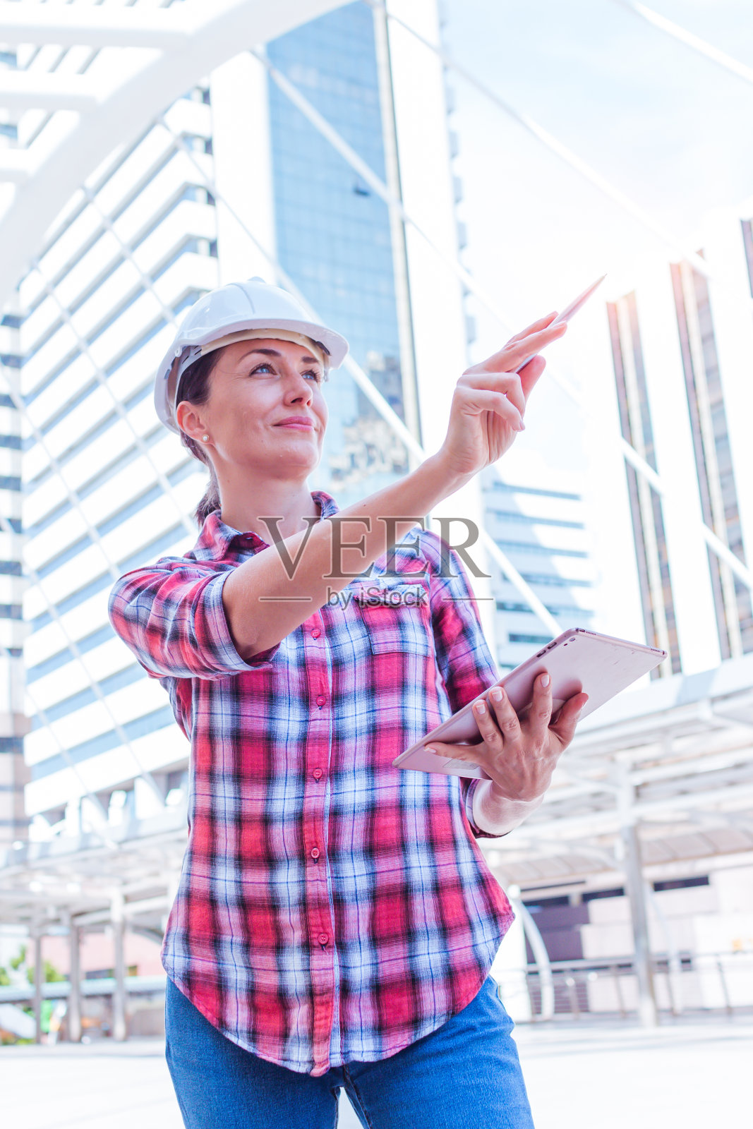 工业建筑工程师戴安全帽工作,并在建筑外面使用数字平板电脑。工程工具和施工概念。企业行业的概念。副本的空间。照片摄影图片