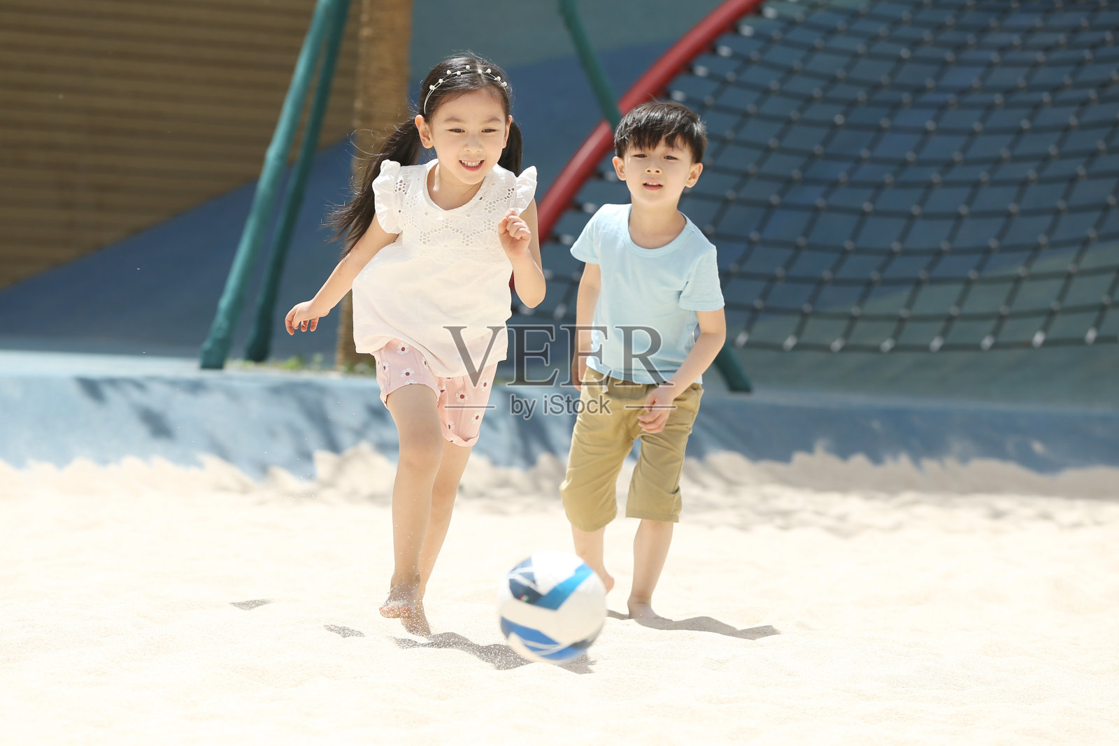 儿童在沙子里踢球照片摄影图片