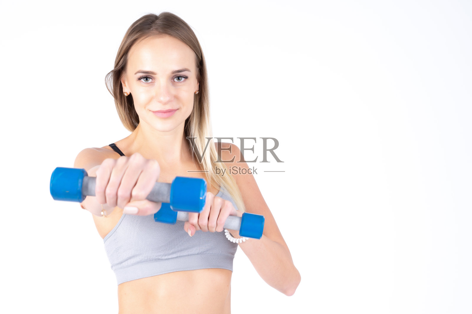 漂亮的年轻苗条的女孩,白色背景上的哑铃。新手的运动员照片摄影图片