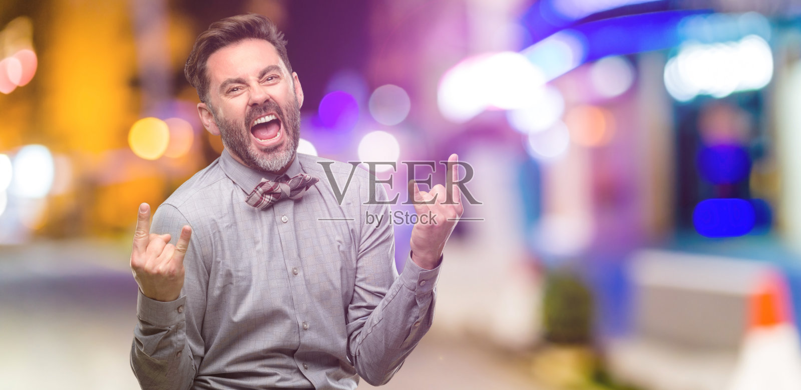 中年男子,蓄着胡子,打着领结,用手做着摇滚的象征,叫喊着,庆祝着照片摄影图片