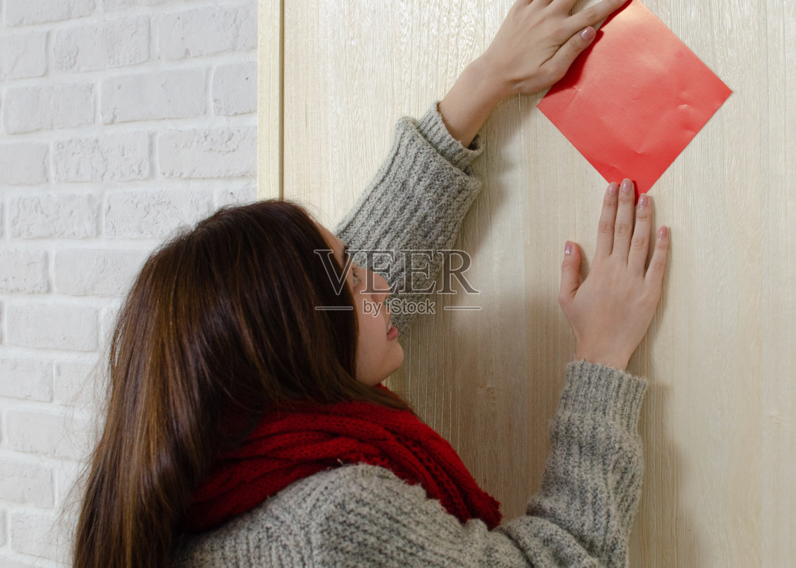 年轻的亚洲妇女贴春联。春节时,在门上或墙上贴春联是中国文化的传统,而且会持续很多年照片摄影图片