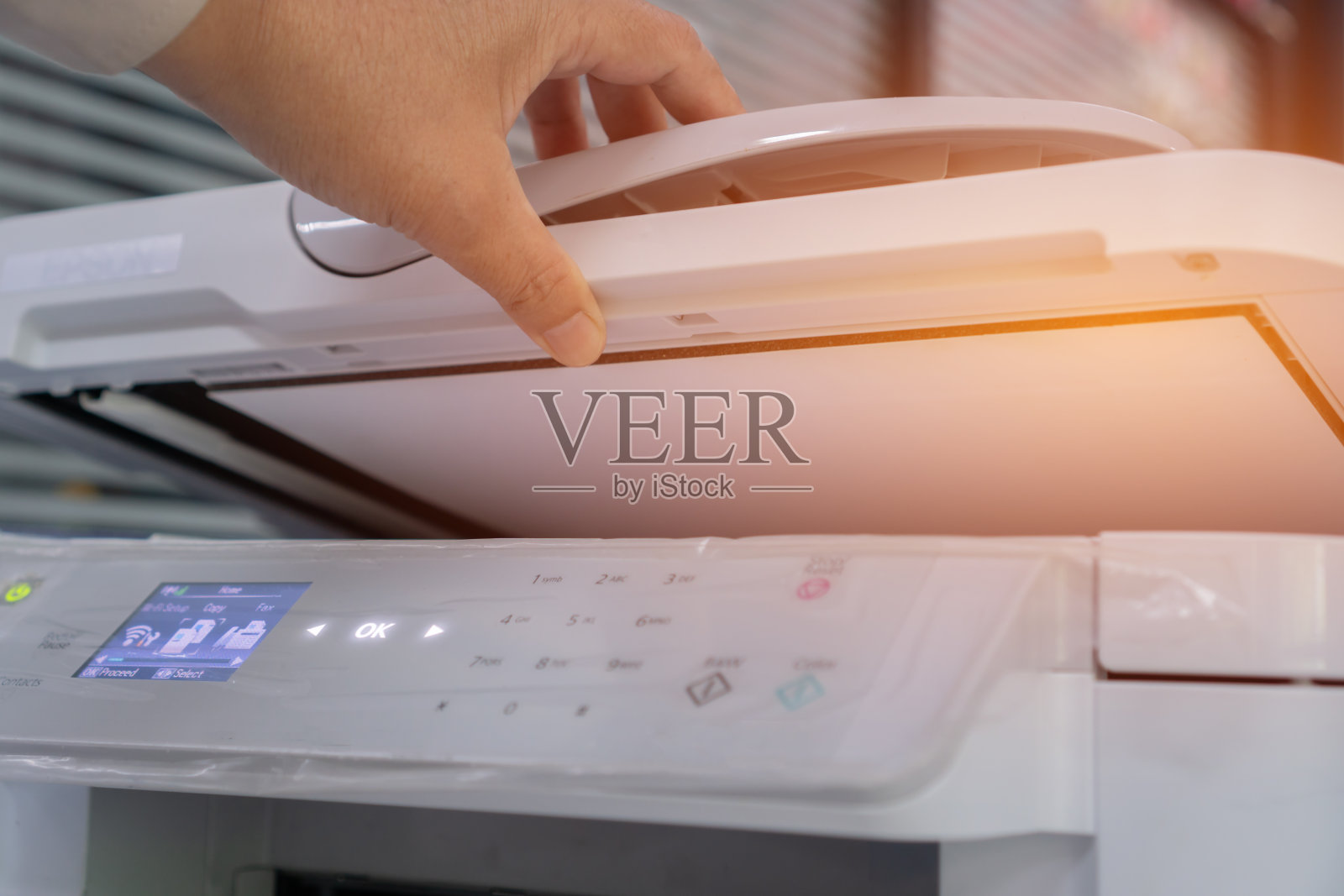 商务文件概念:女商人在忙碌的办公桌上,在激光打印机上打印纸张的过程中工作。软焦点照片摄影图片