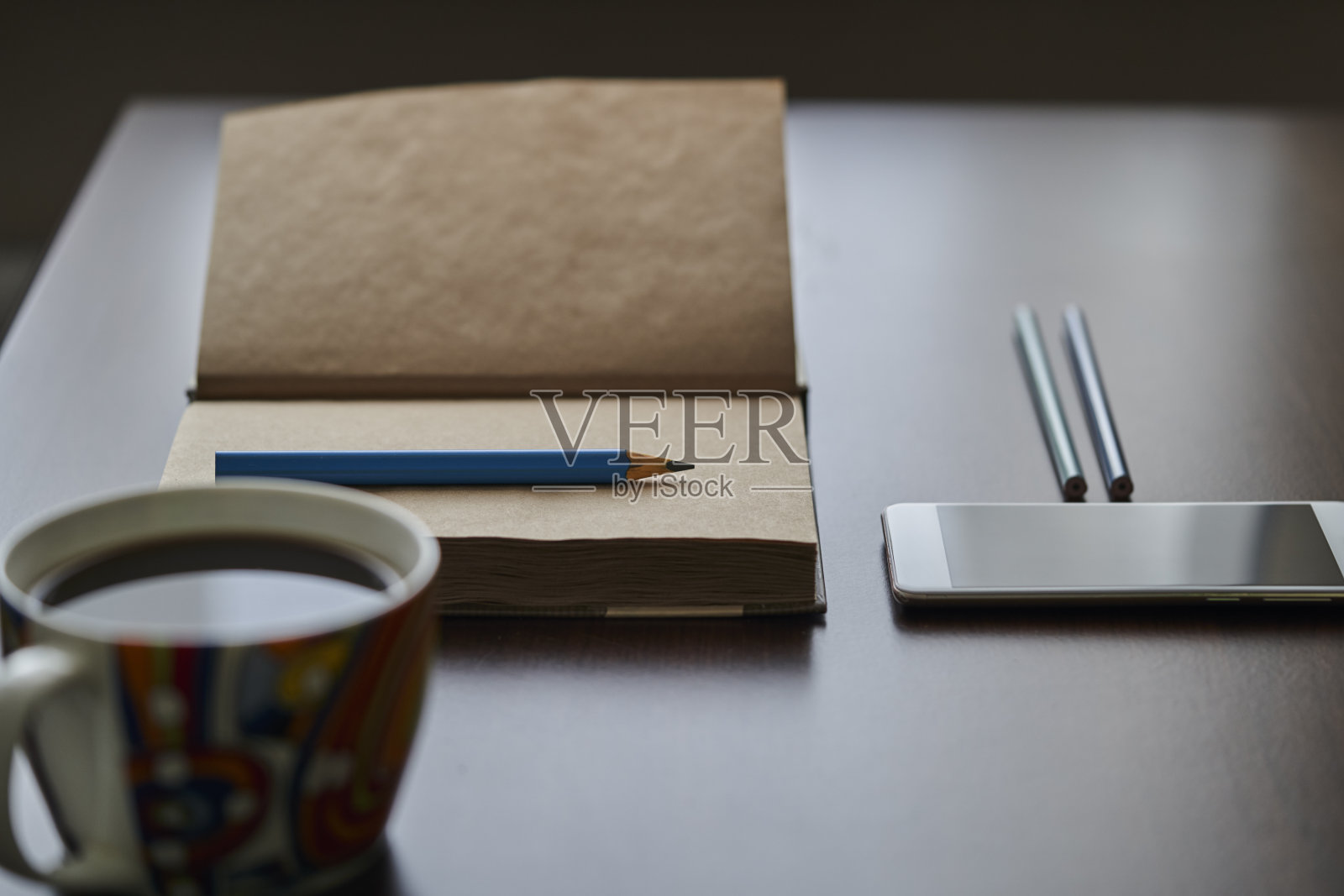 再生纸笔记本,铅笔,手机和一杯咖啡放在一个黑色的桌子上。办公桌,笔记本,铅笔,智能手机和一杯咖啡。照片摄影图片