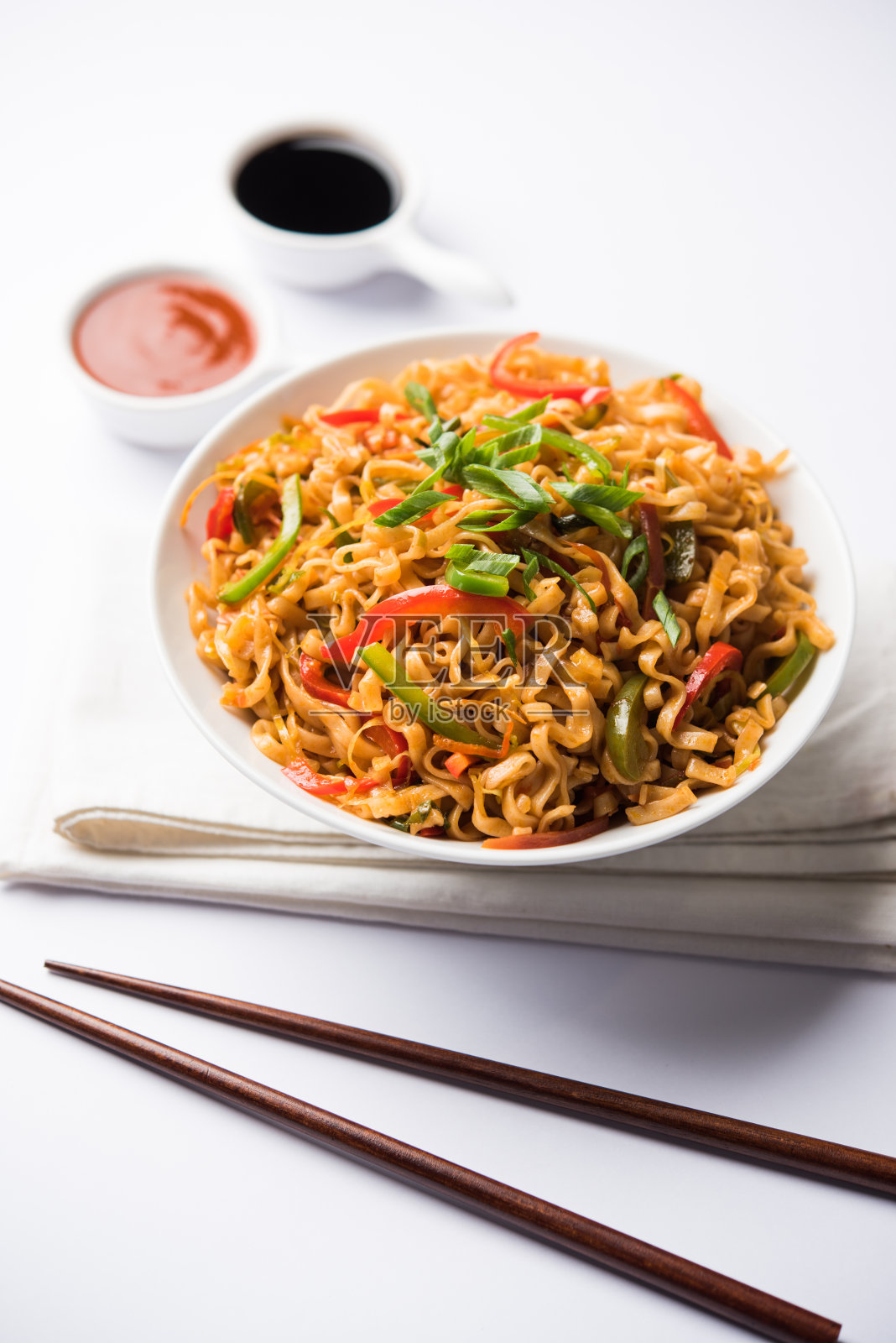 四川菜面是一种用酱料和蔬菜煸炒的客家扁面,味道辛辣可口。用筷子。有选择性的重点照片摄影图片