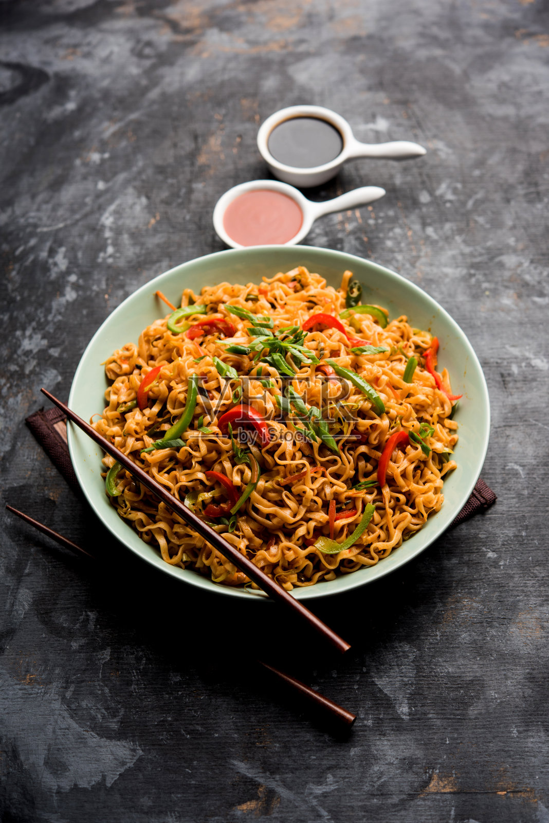 四川菜面是一种用酱料和蔬菜煸炒的客家扁面,味道辛辣可口。用筷子。有选择性的重点照片摄影图片