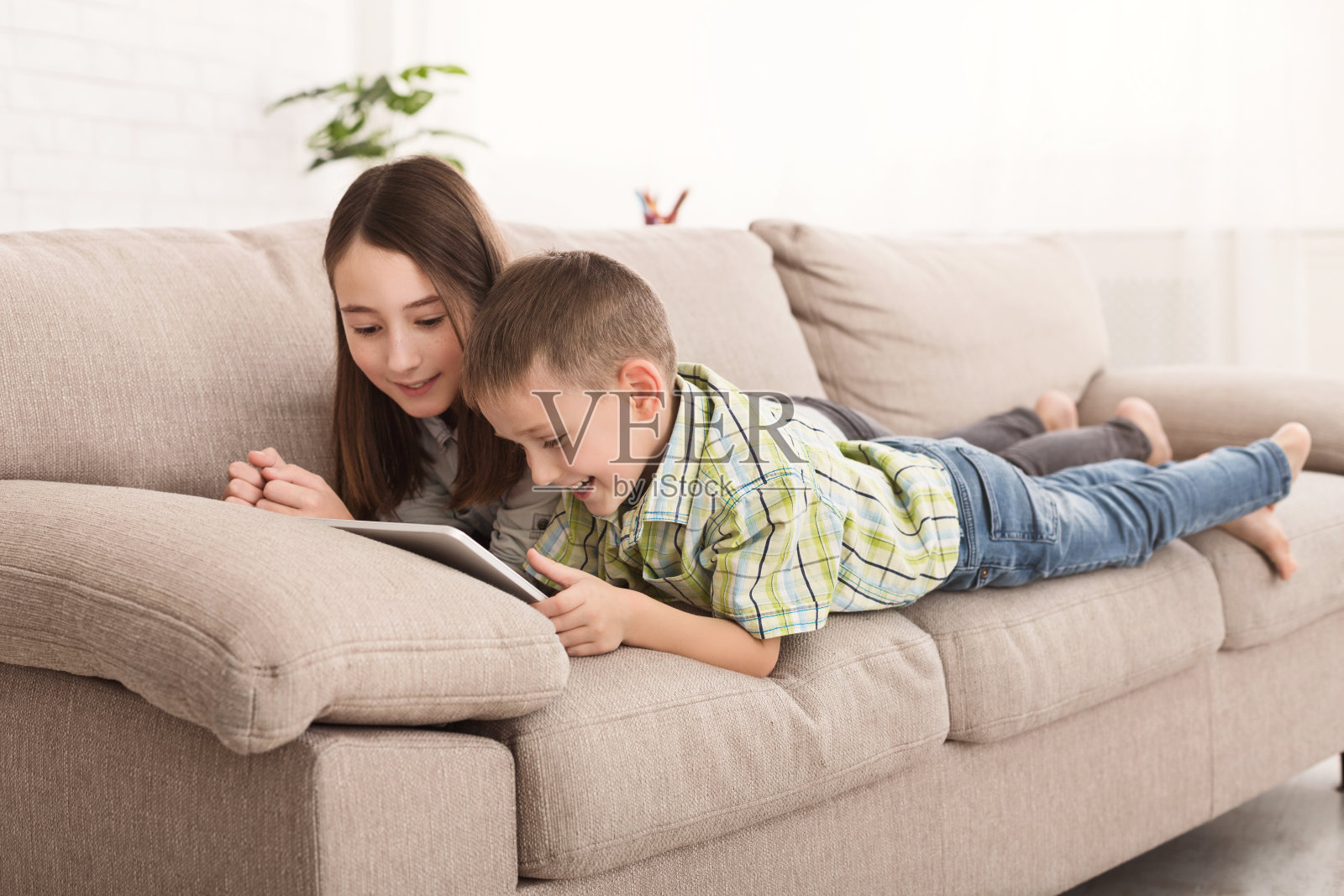 快乐的兄弟姐妹一起在平板电脑上看动画片照片摄影图片